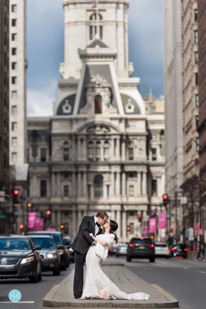 Bride and groom pose in front of Central Hall on Broad Street in Philadelphia