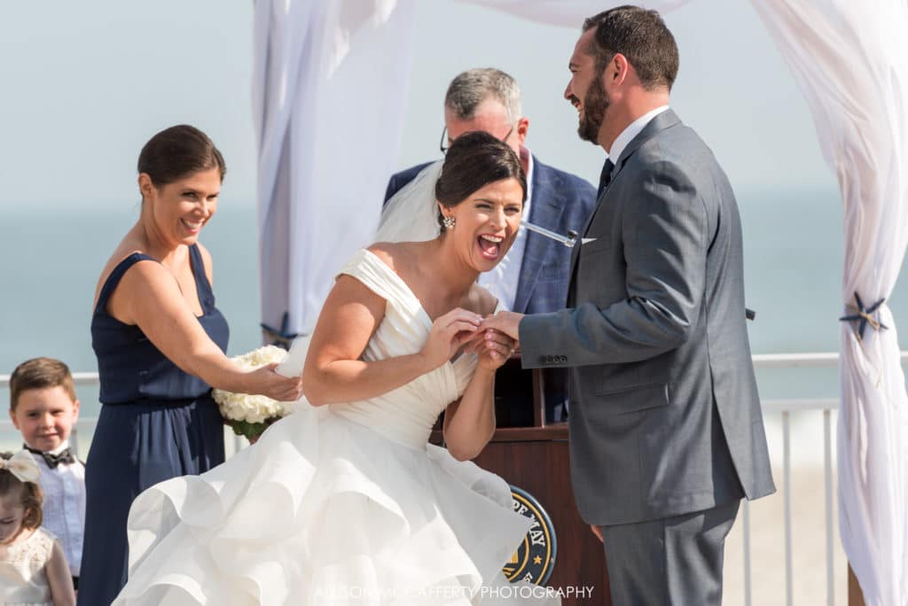 Bride laughing as she puts the ring on her husband