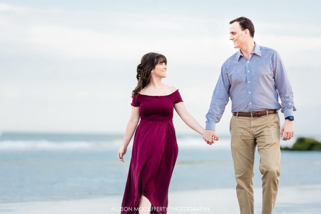 couple holding hands on the beach walking