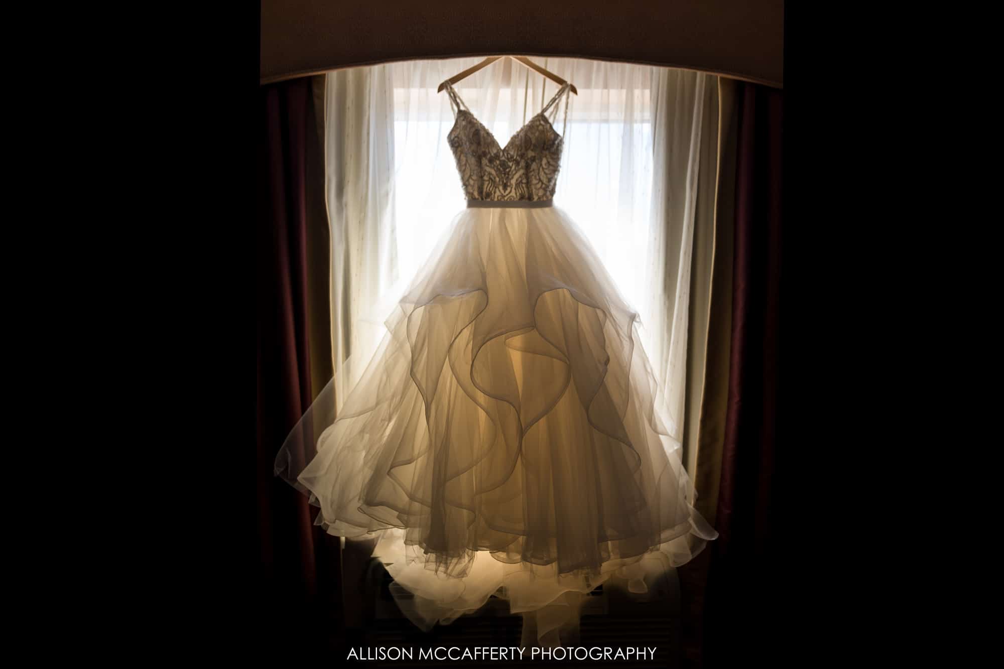 Wedding gown hanging in front of a window