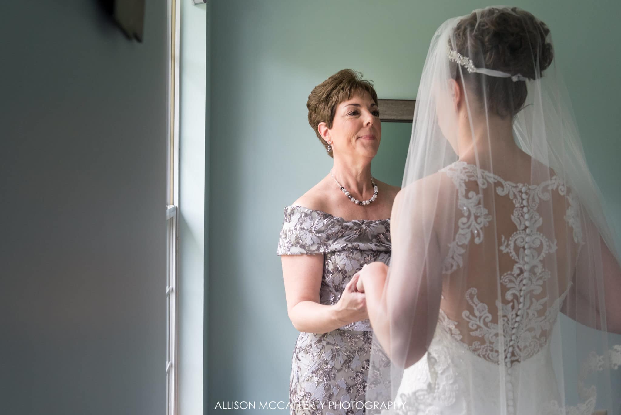 Photo of bride and her mother in front of a window