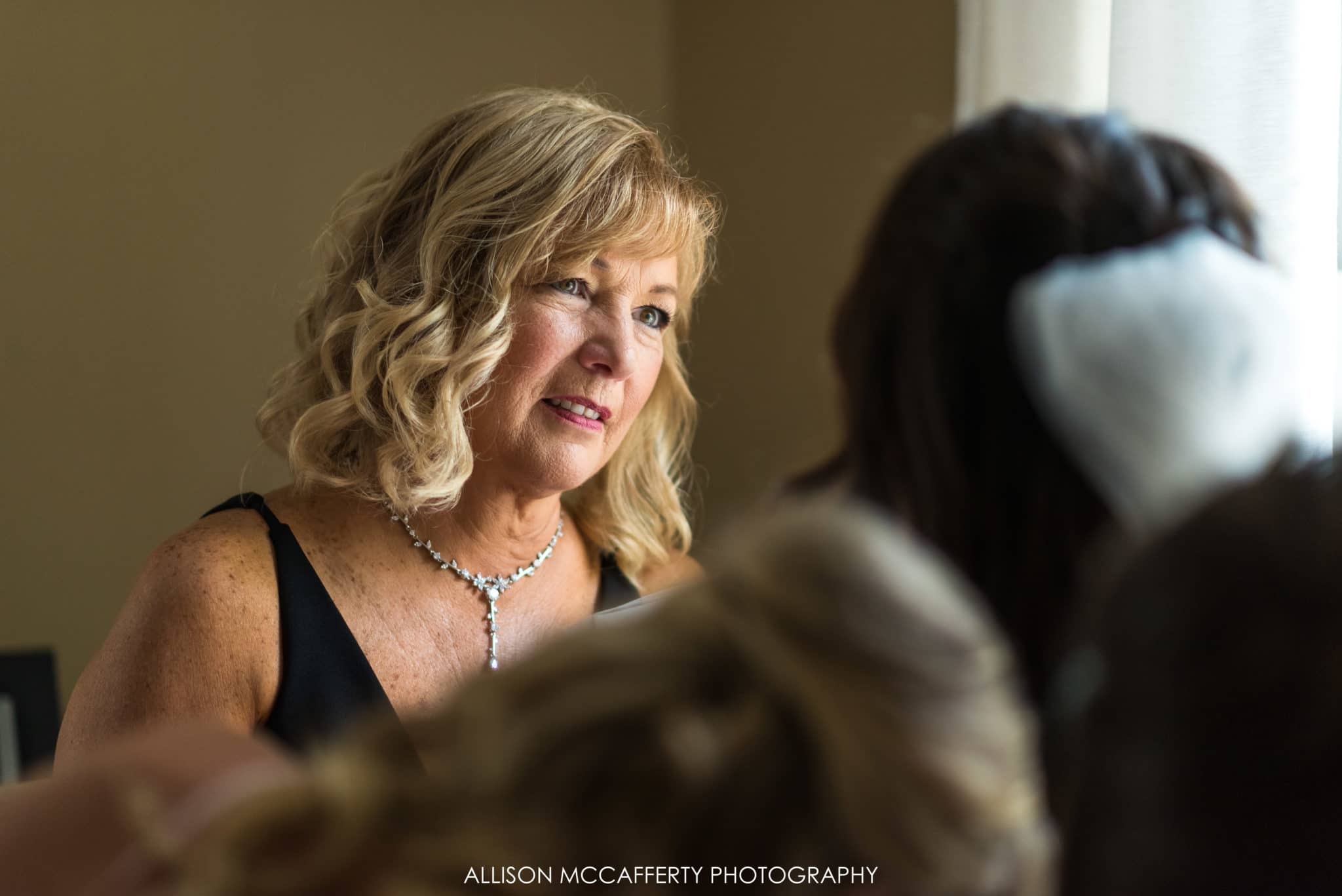 mom looking at her daughter as she gets dressed on her wedding day