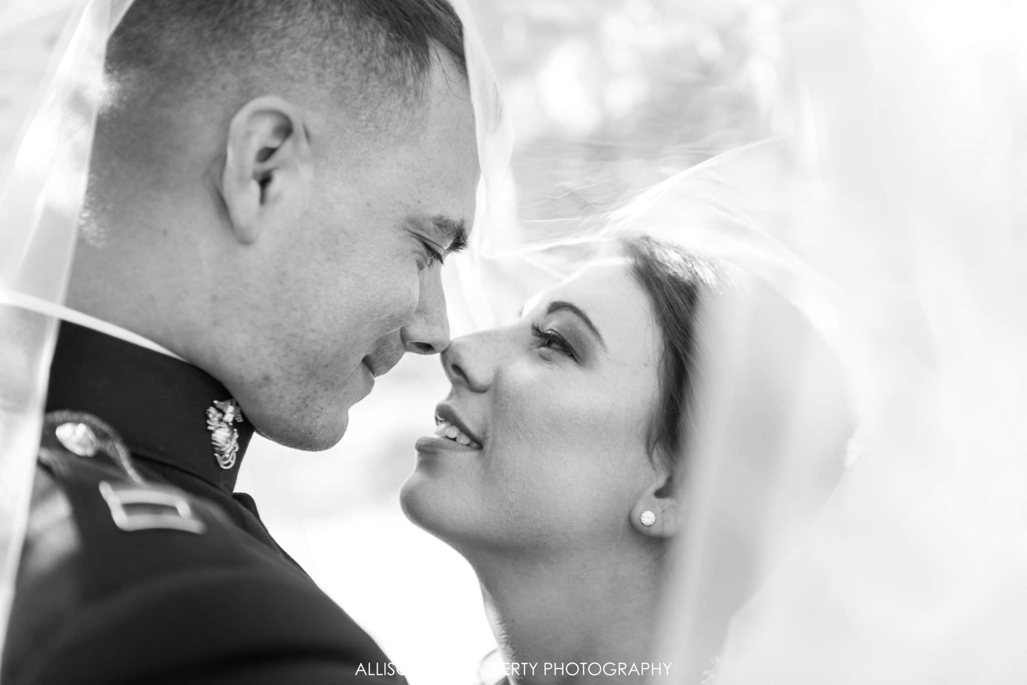 black and white photo of bride and groom under veil