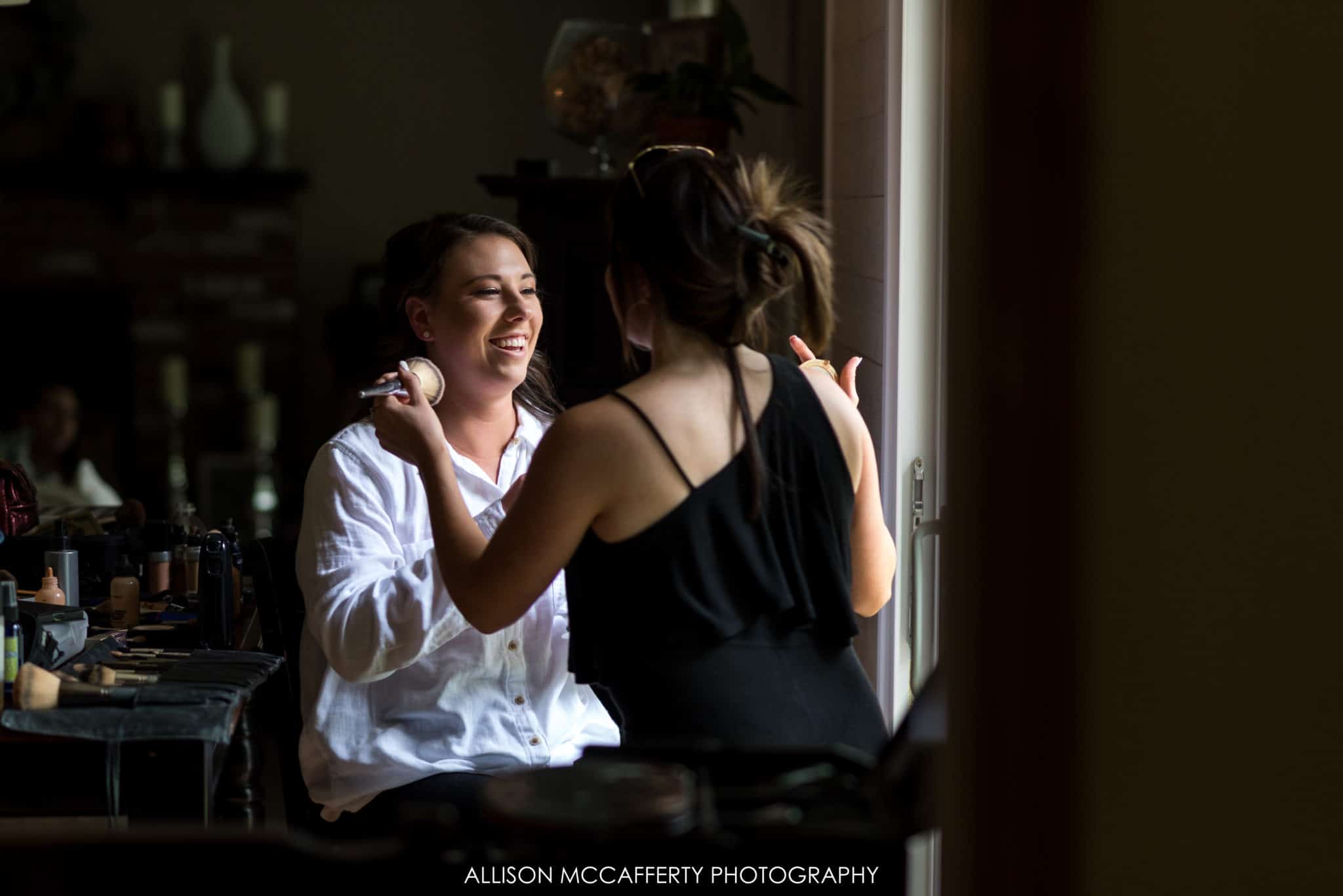 bride sitting in window light getting makeup done