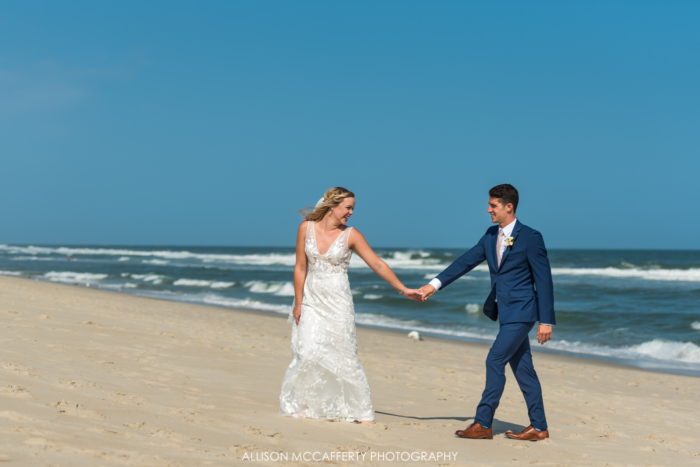 Bride leading groom up the beach in Beach Haven, NJ