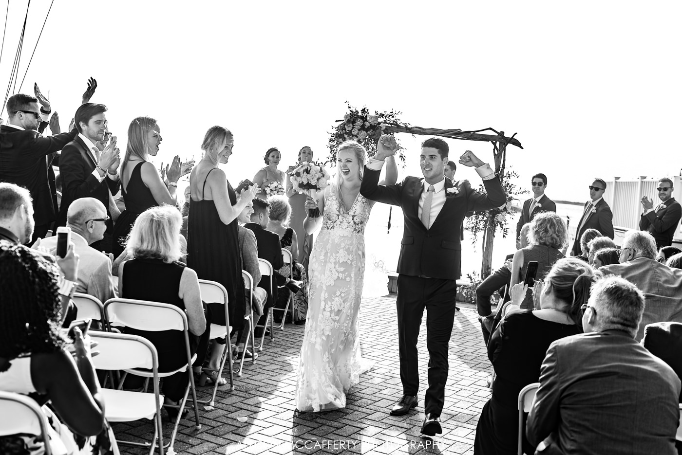 Black and white photo of newly wed couple walking out of their ceremony at Brant Beach Yacht Club