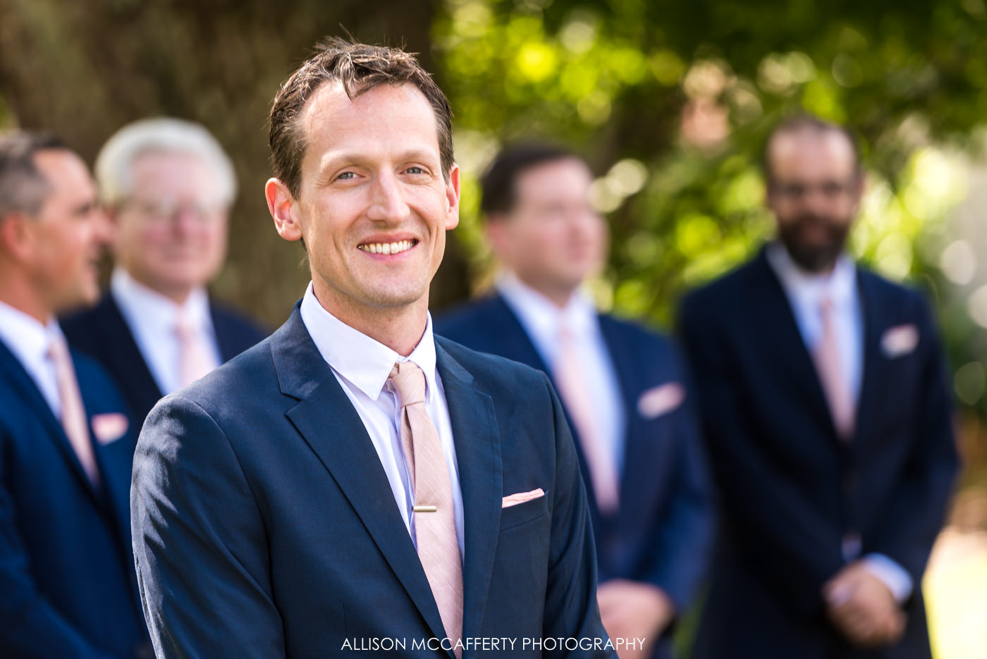 Photo of groom in navy suit and pink tie