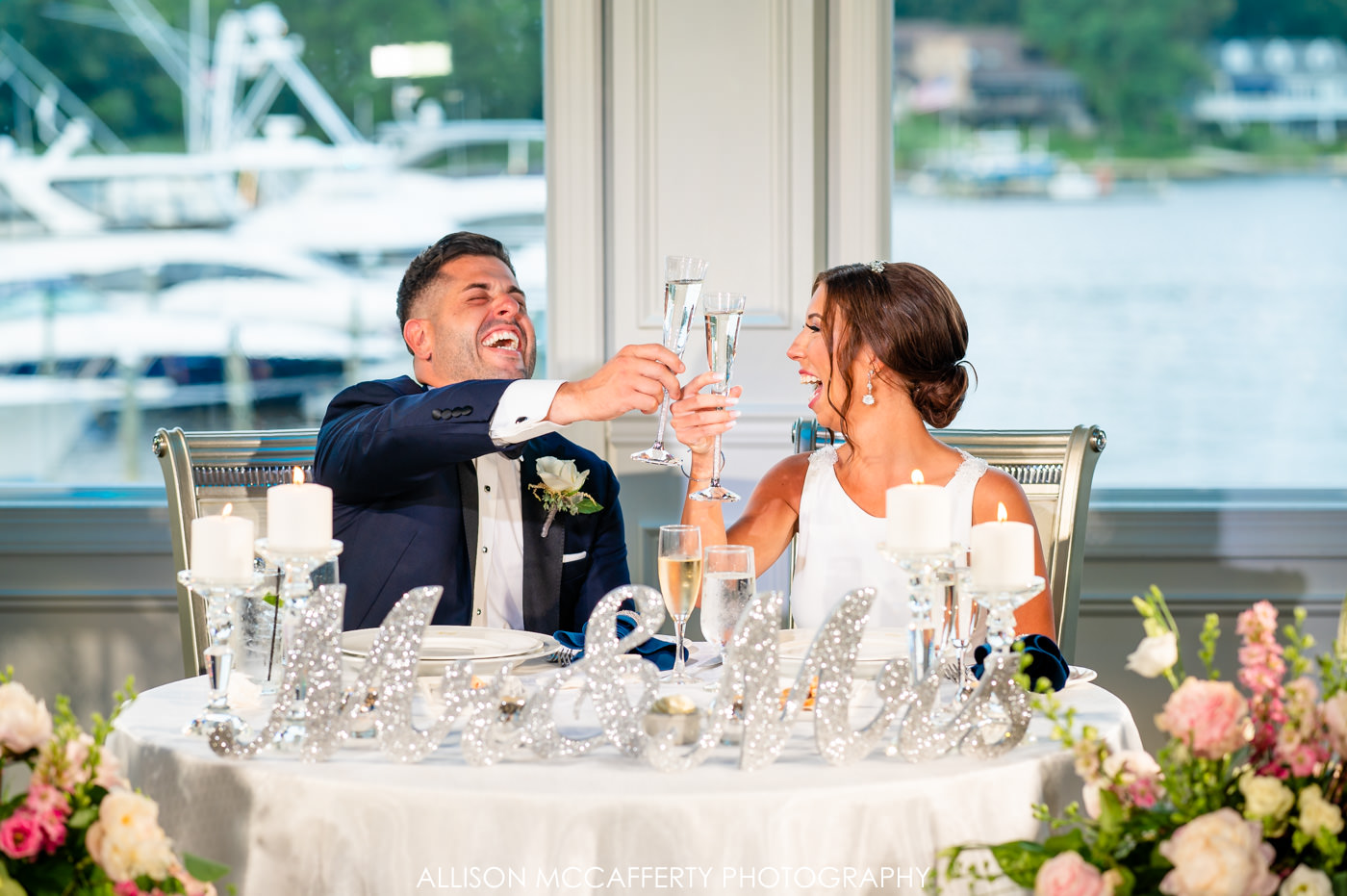 bride and groom toasting with champagne flutes during speeches at their Crystal Point Yacht Club wedding
