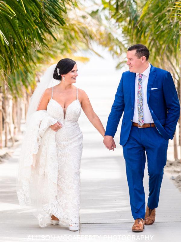 Bride and groom holding hands walking through a palm trees before their wedding at ICONA Diamond Beach in Wildwood NJ