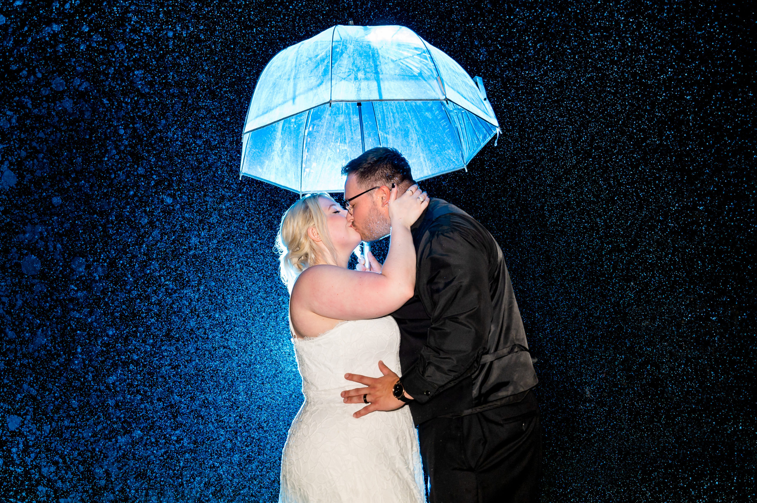 Nighttime wedding photo in the rain with an umbrella at Vitners Pavilion by Valenzano Winery in Shamong NJ