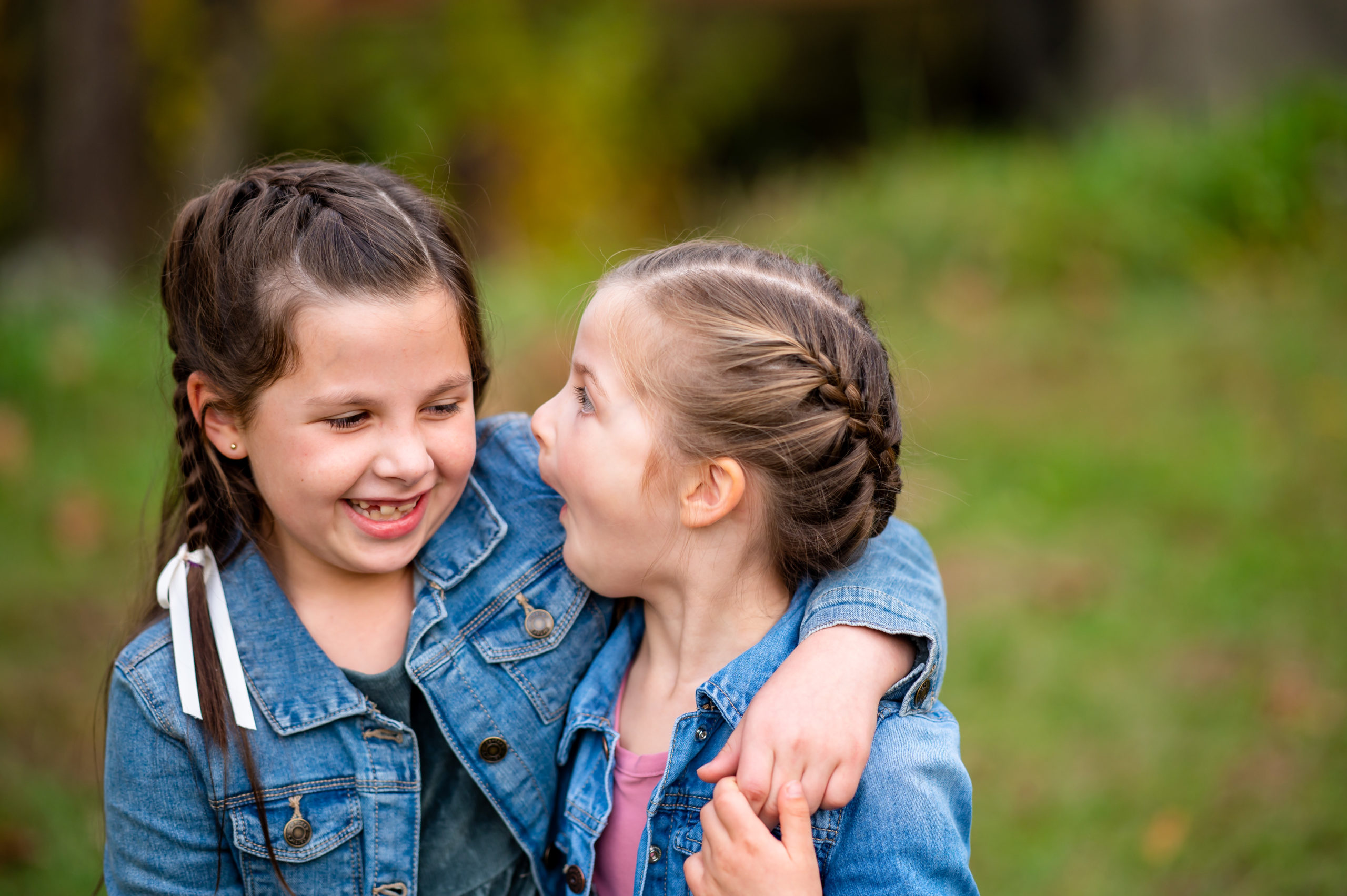 Two young girls wearing jean jackets laughing during a family photo shoot at Kirby's Mill in Medford NJ