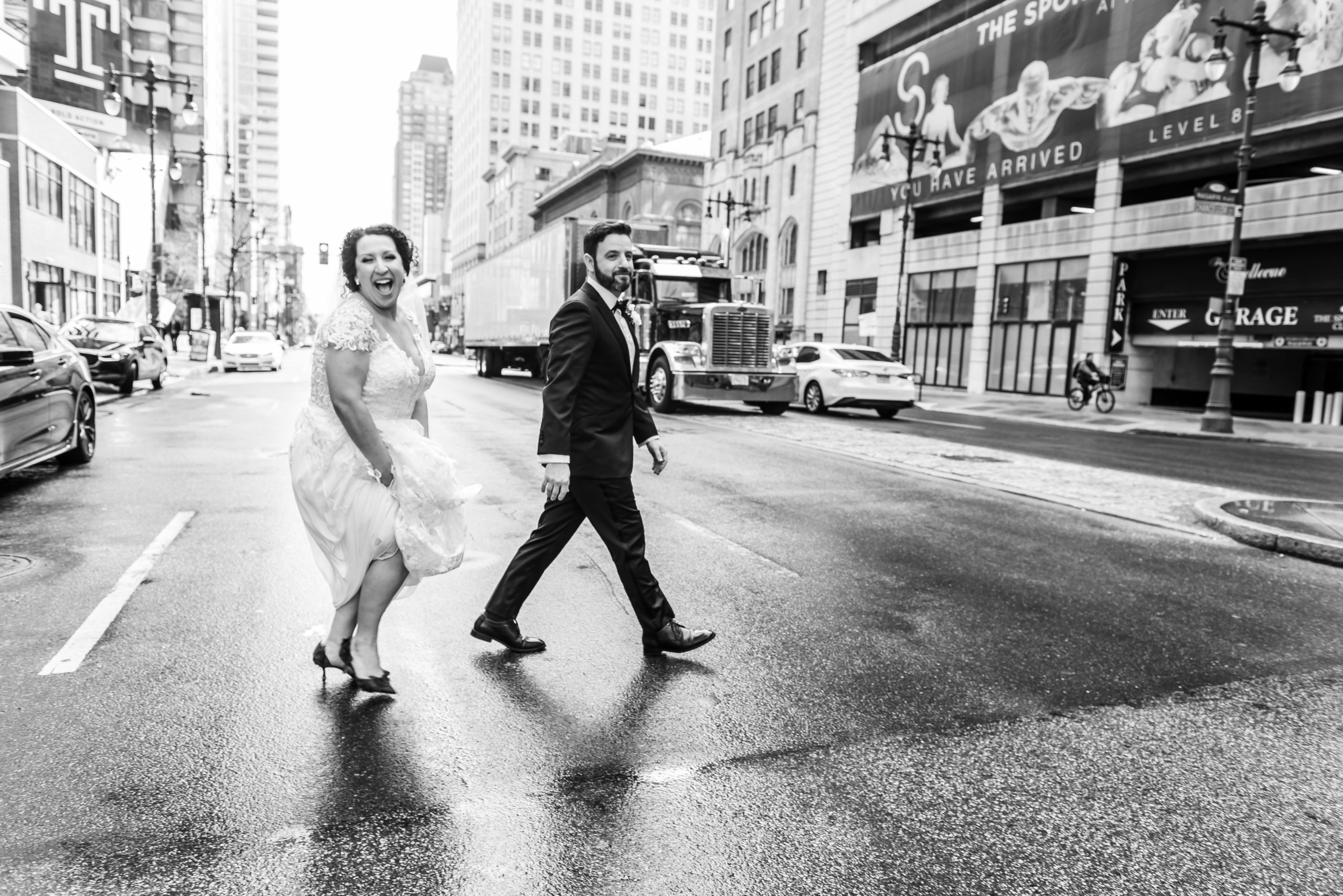 Wedding couple walking across Broad Street in Philadelphia in the rain