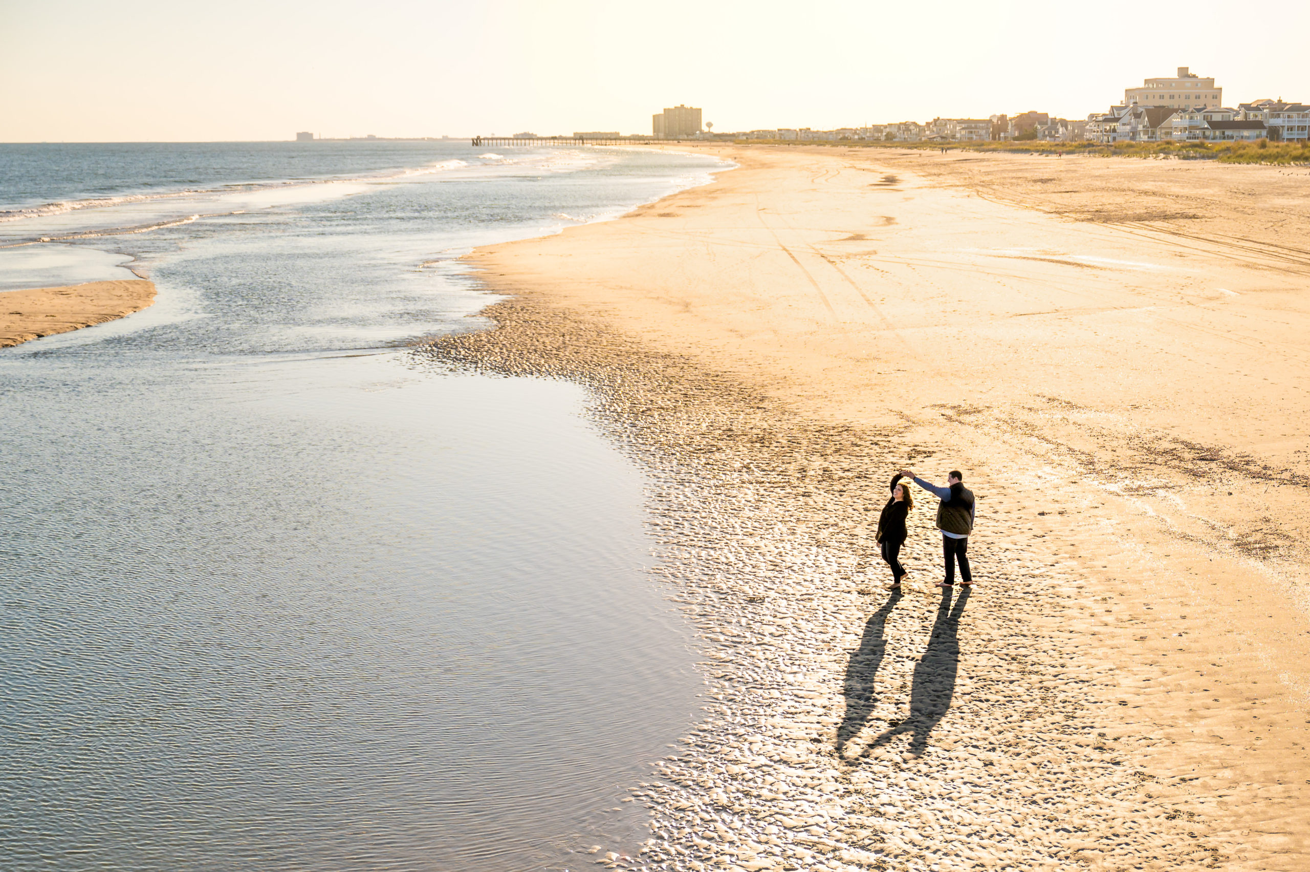 Engagement photo of a couple walking on a Jersey Shore beach taken from a high angle