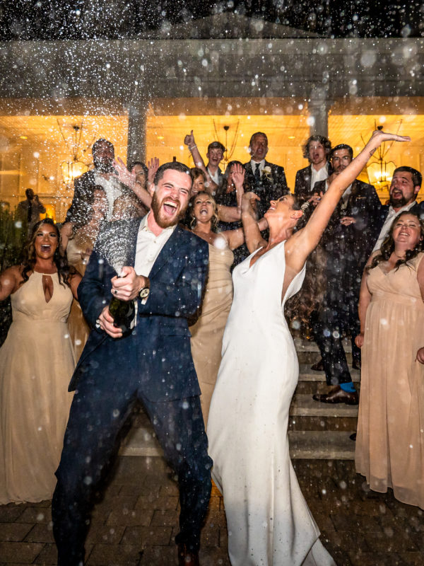 Wedding photo of a group of people spraying champagne in front of Seaview Hotel in Galloway NJ