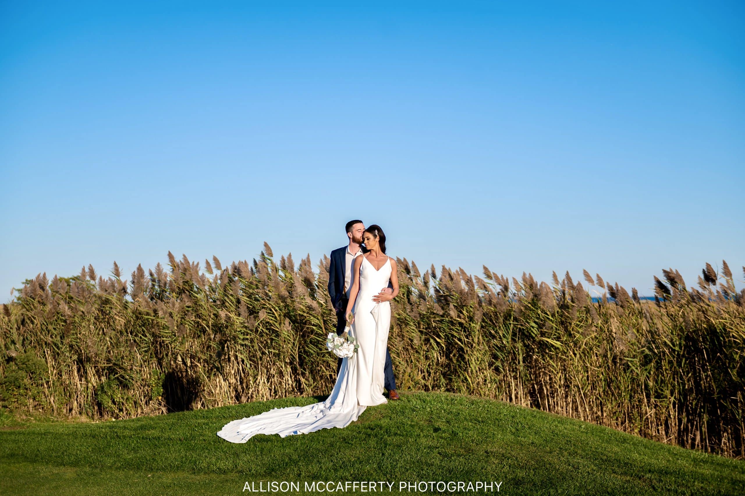 Wedding photo of a couple standing in front of the reeds on the golf course across the street from Seaview Hotel in Galloway NJ