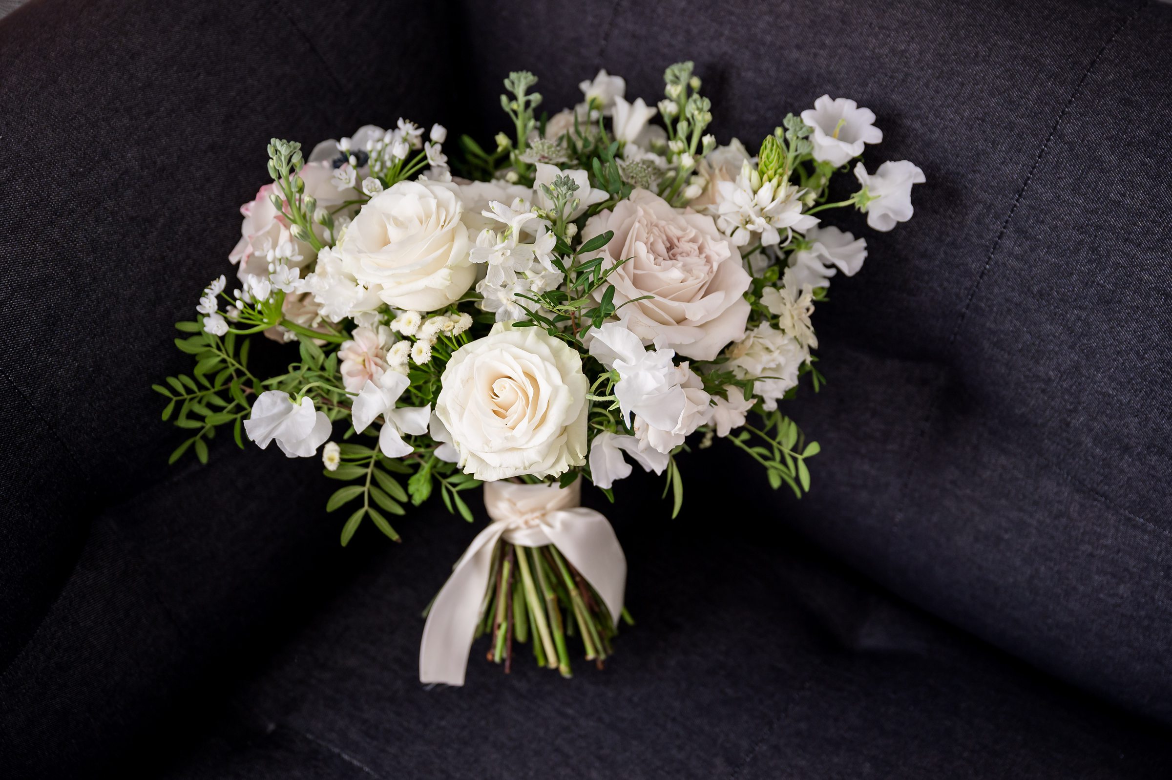 At Lilah Events, a bouquet of white and pink flowers elegantly decorates a gray couch.