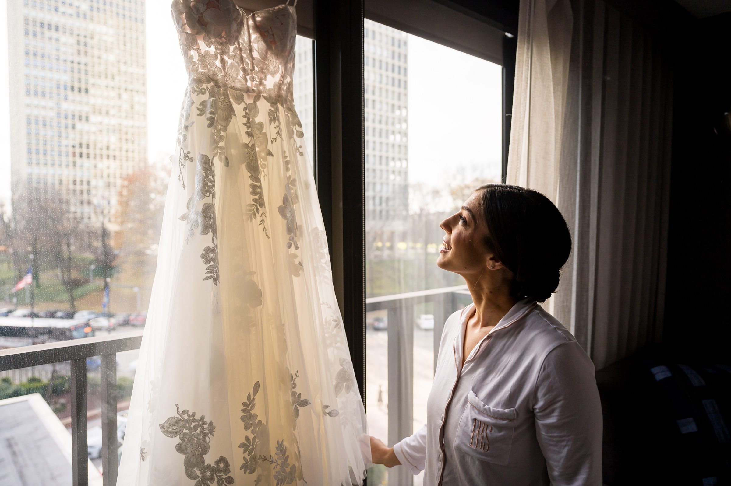 A bride admiring her wedding dress by a window at Lilah Events.