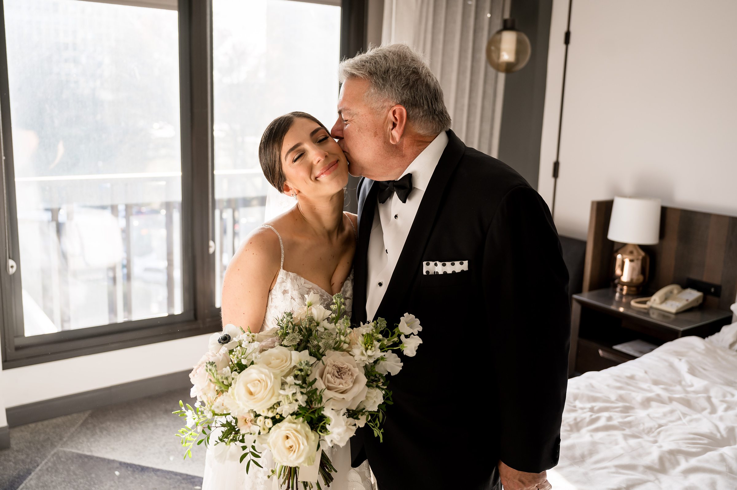 A bride and her father sharing a sweet moment in a hotel room during a Lilah Events wedding.