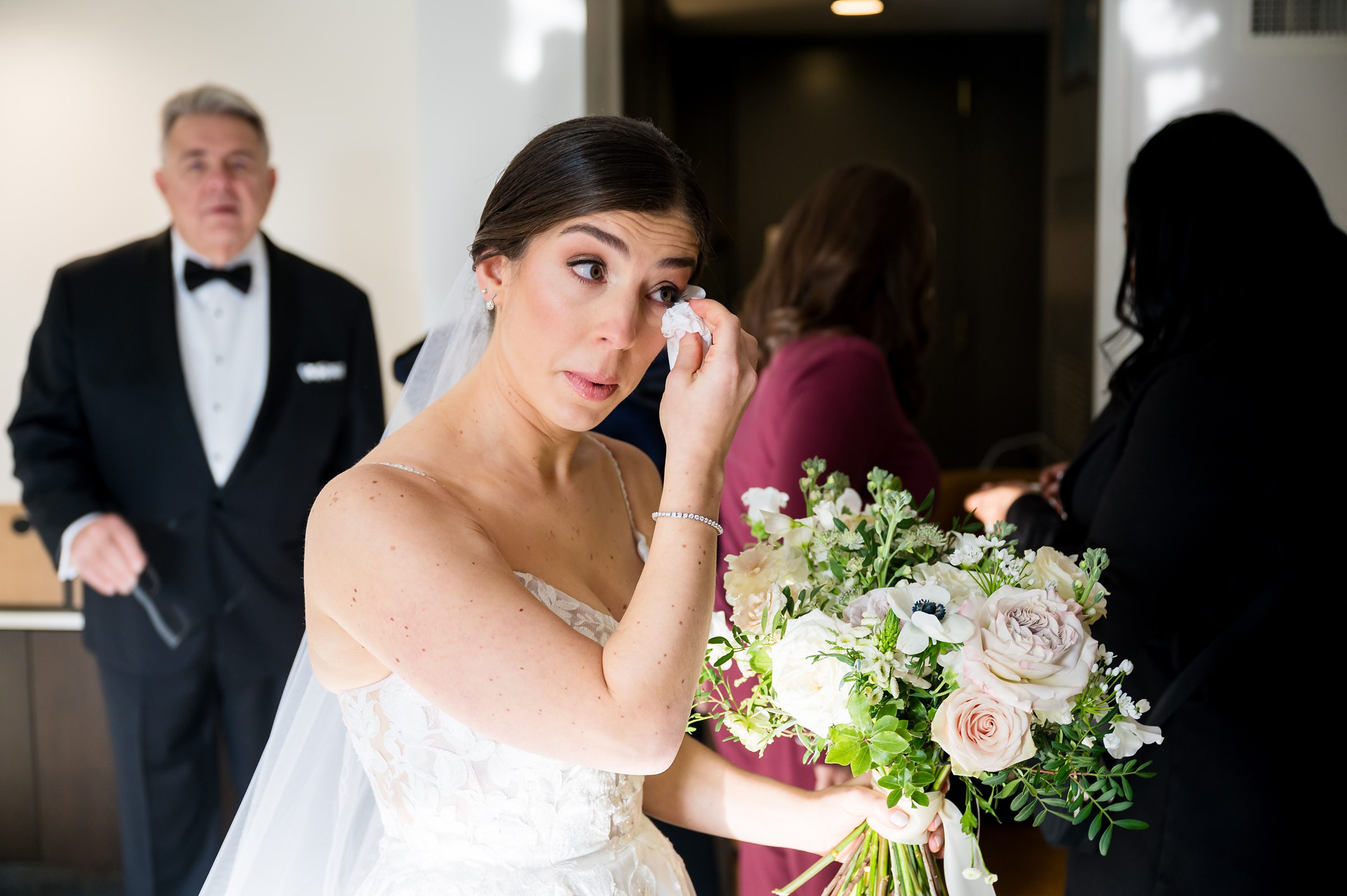 At a Lilah Events wedding, the bride gazes lovingly at her bouquet with the man standing behind her.