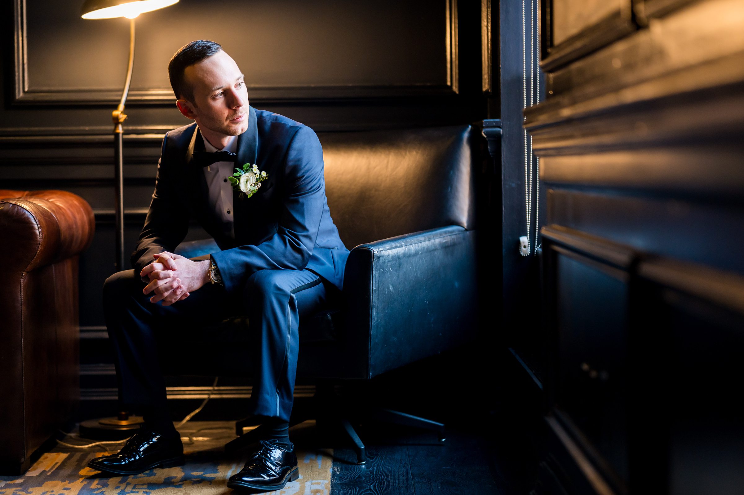 A groom in a tuxedo sitting on a chair at a Lilah Events wedding.