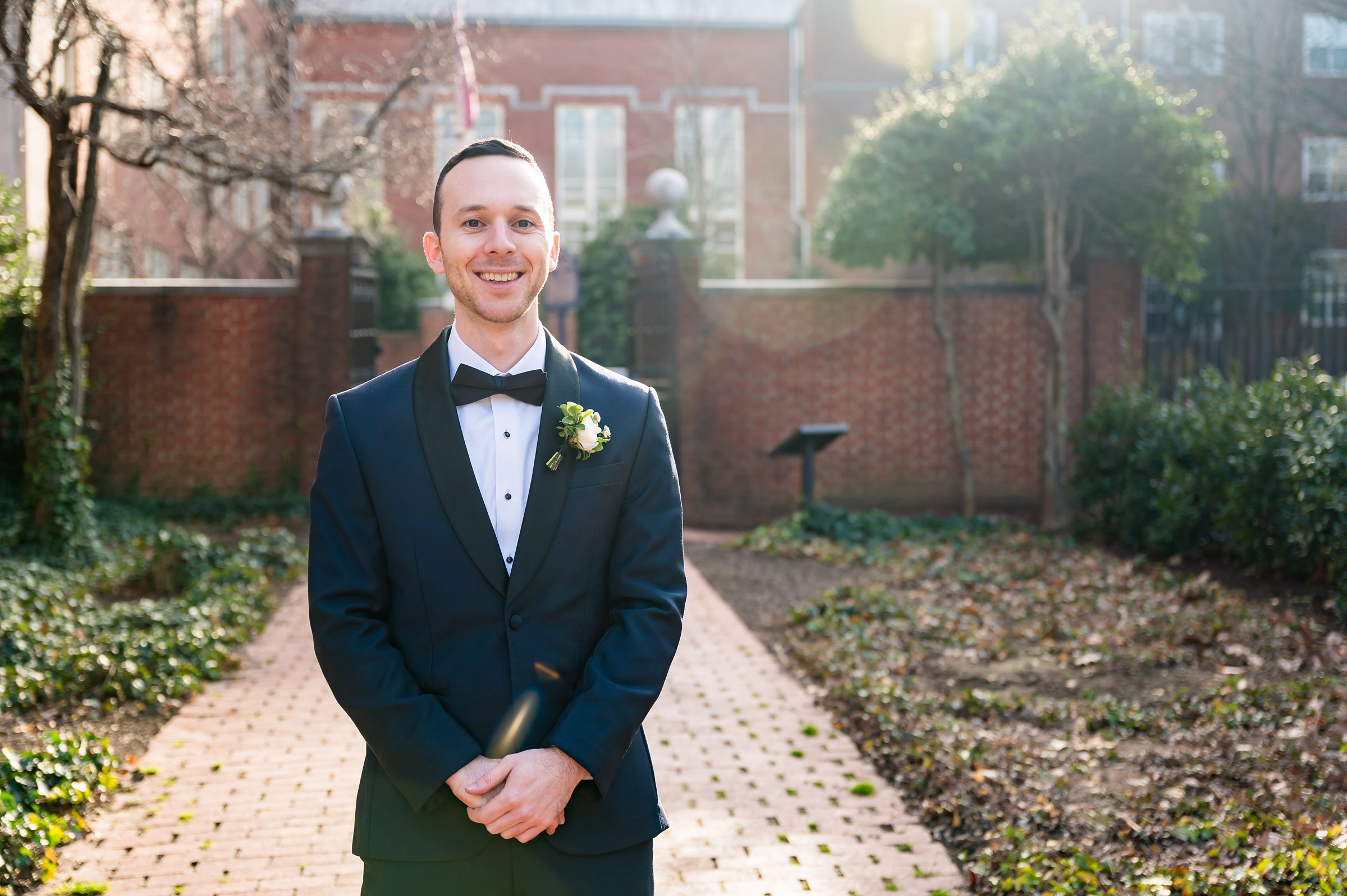 At the Lilah Events wedding, a groom in a tuxedo stands in front of a brick walkway.
