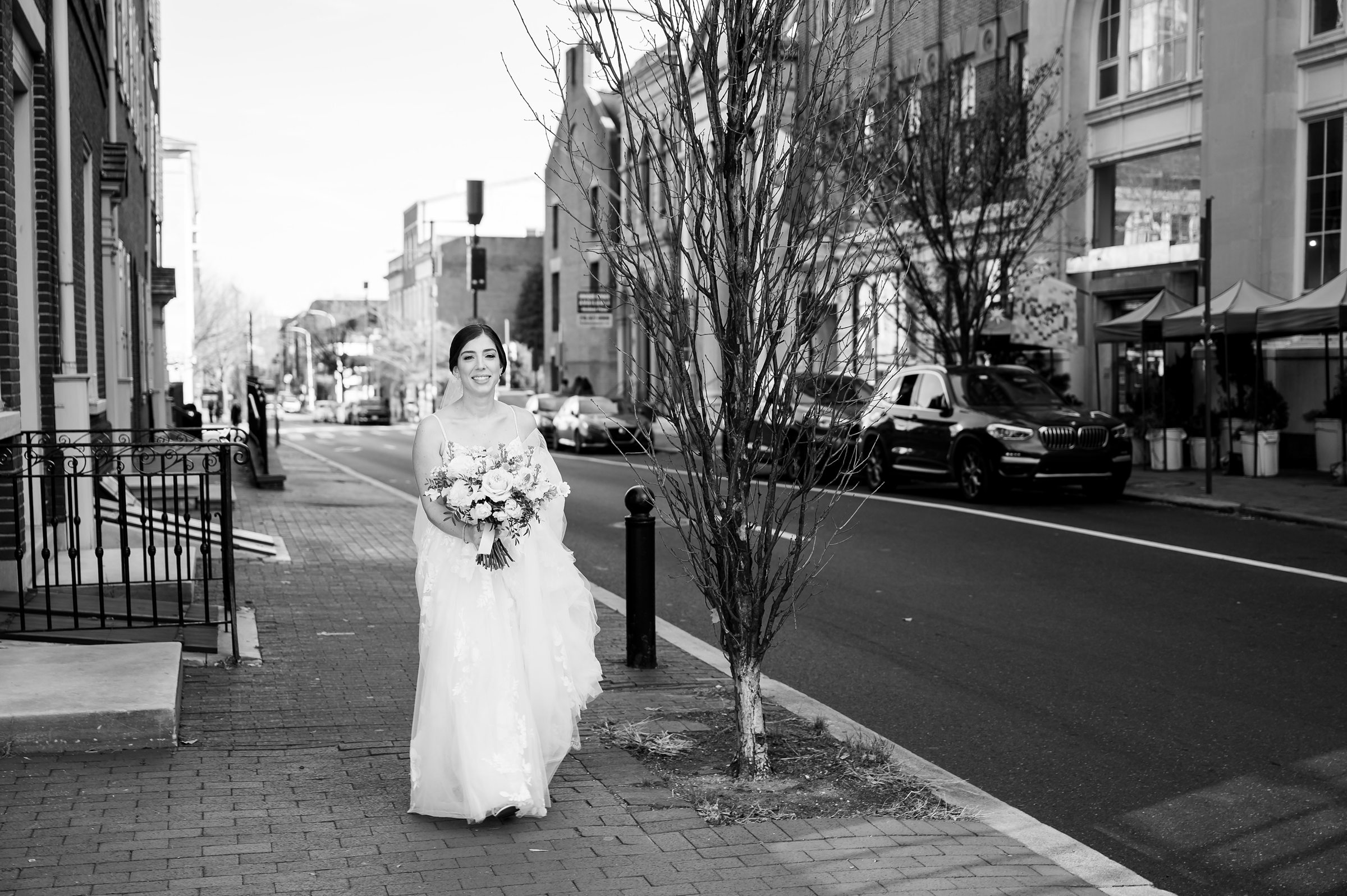 A bride walks down a city street in her stunning wedding dress, showcasing the elegance of Lilah Events.
