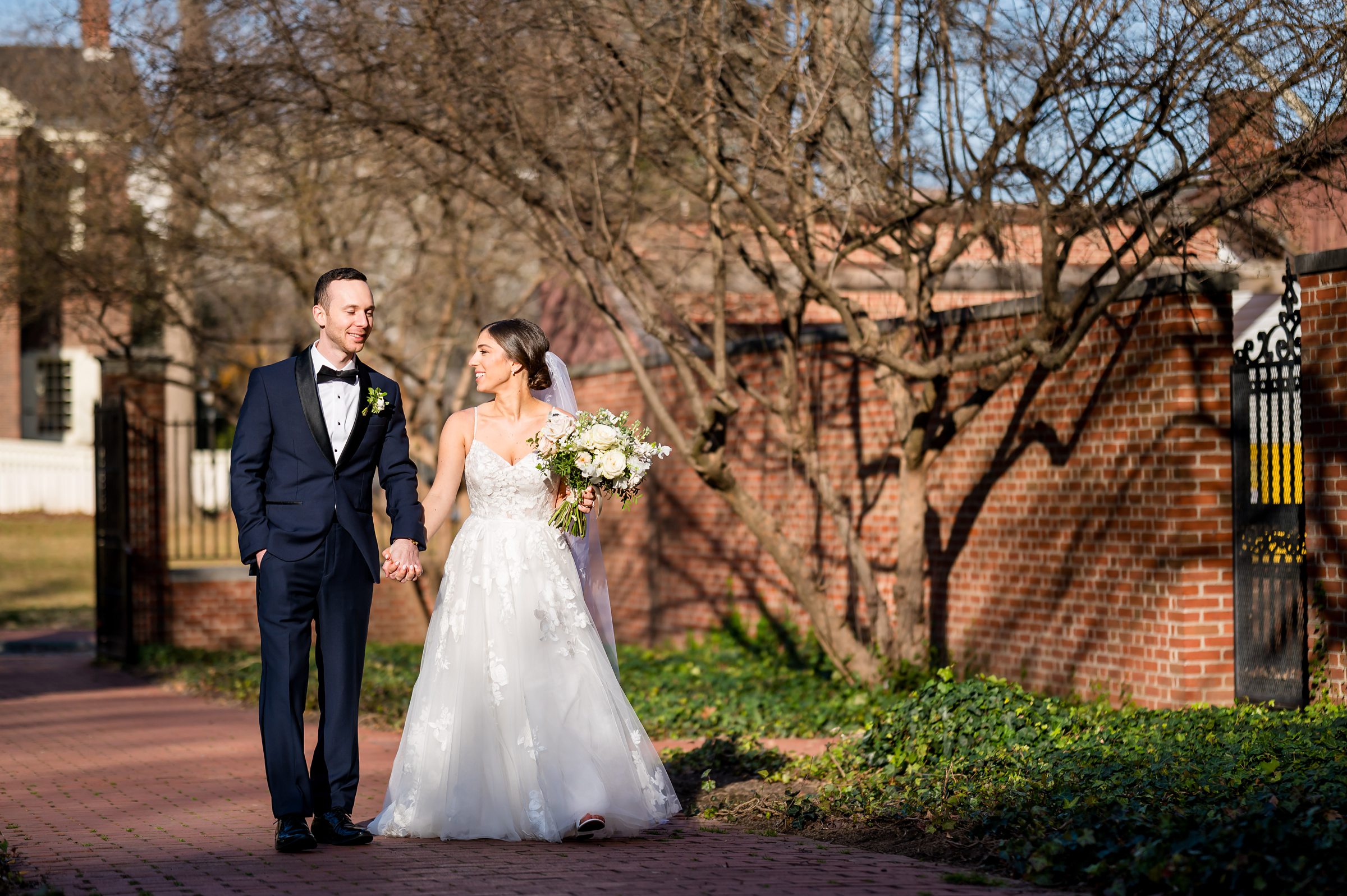 A bride and groom walking down a brick walkway at their Lilah Events wedding.