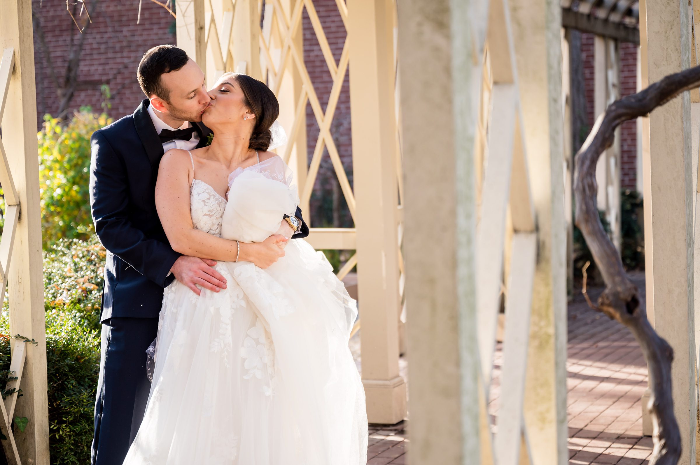 A bride and groom share a kiss in front of a gazebo at a Lilah Events wedding.