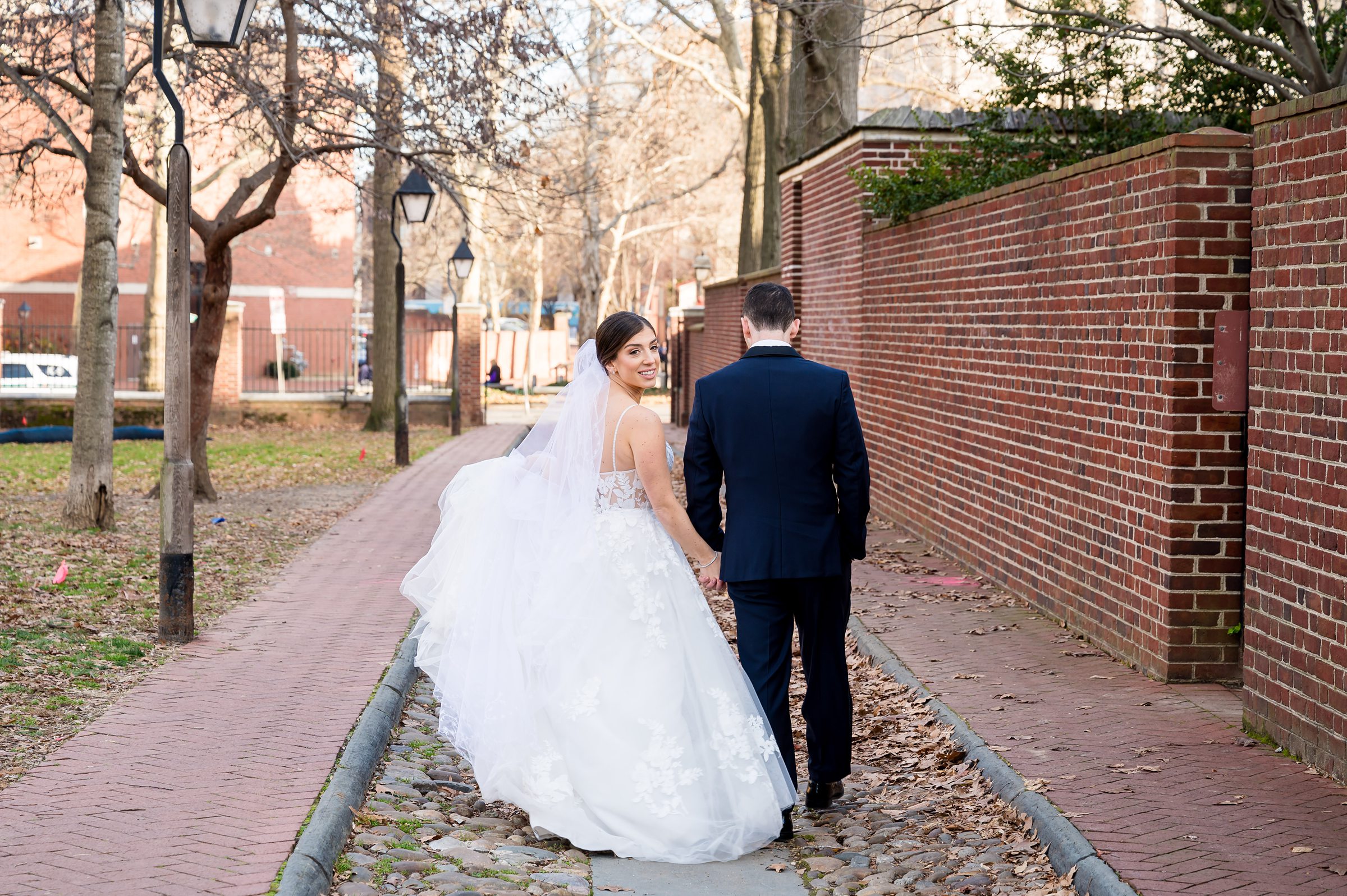 A bride and groom walking down a brick walkway at their Lilah Events wedding.