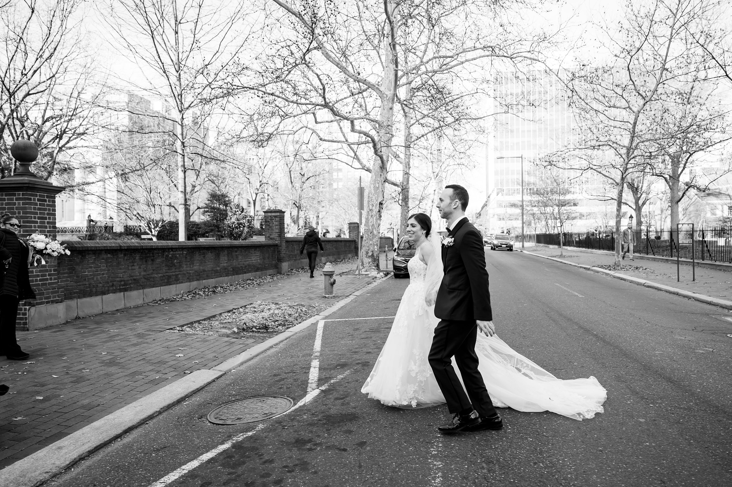 A bride and groom crossing the street in front of a building during their Lilah Events wedding.