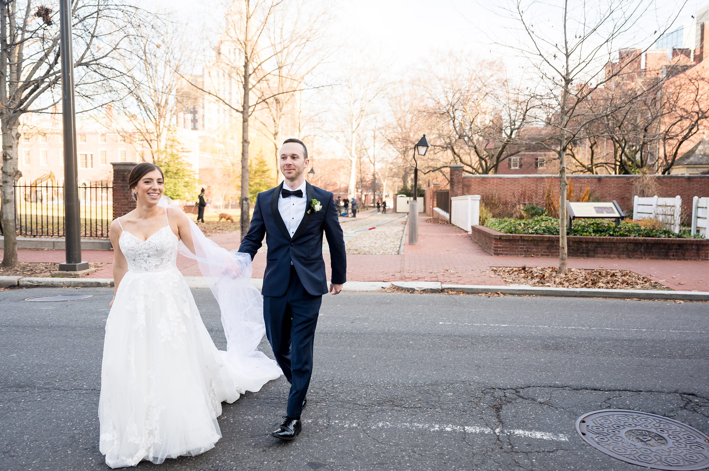 A bride and groom walking down the street in front of a building, captured by Lilah Events.