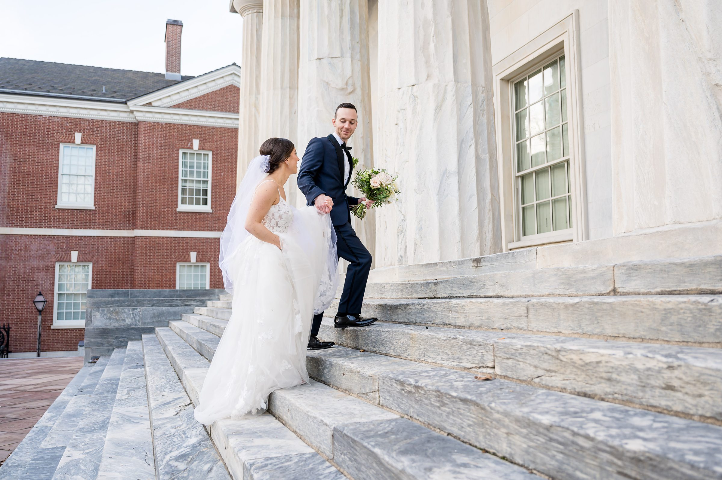 A bride and groom elegantly descending the steps of a building after their Lilah Events wedding.