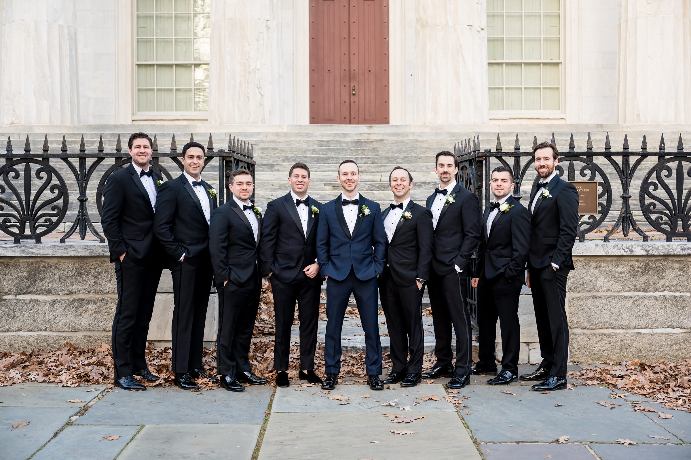 A group of groomsmen posing in front of a building during a Lilah wedding event.