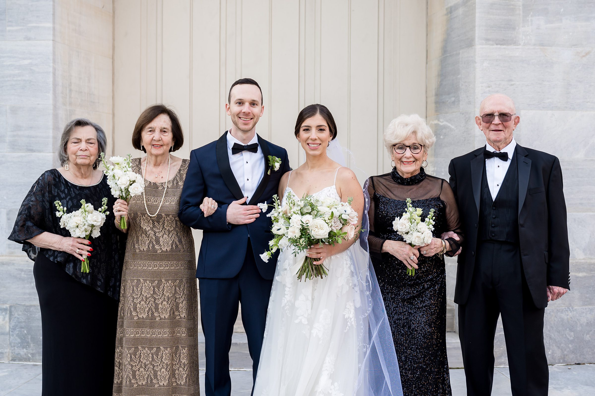 A bride and her family pose for a photo in front of a building during their Lilah Events wedding.