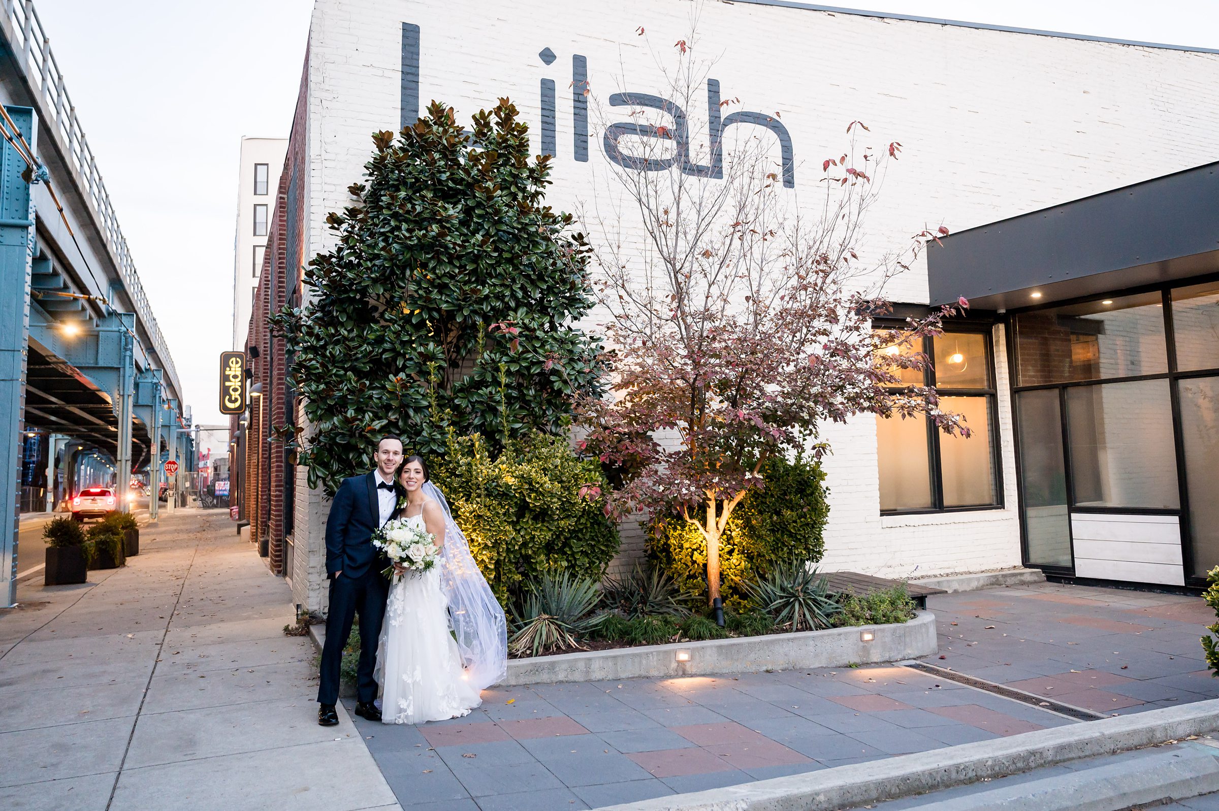 A bride and groom standing in front of the Lilah Events restaurant.