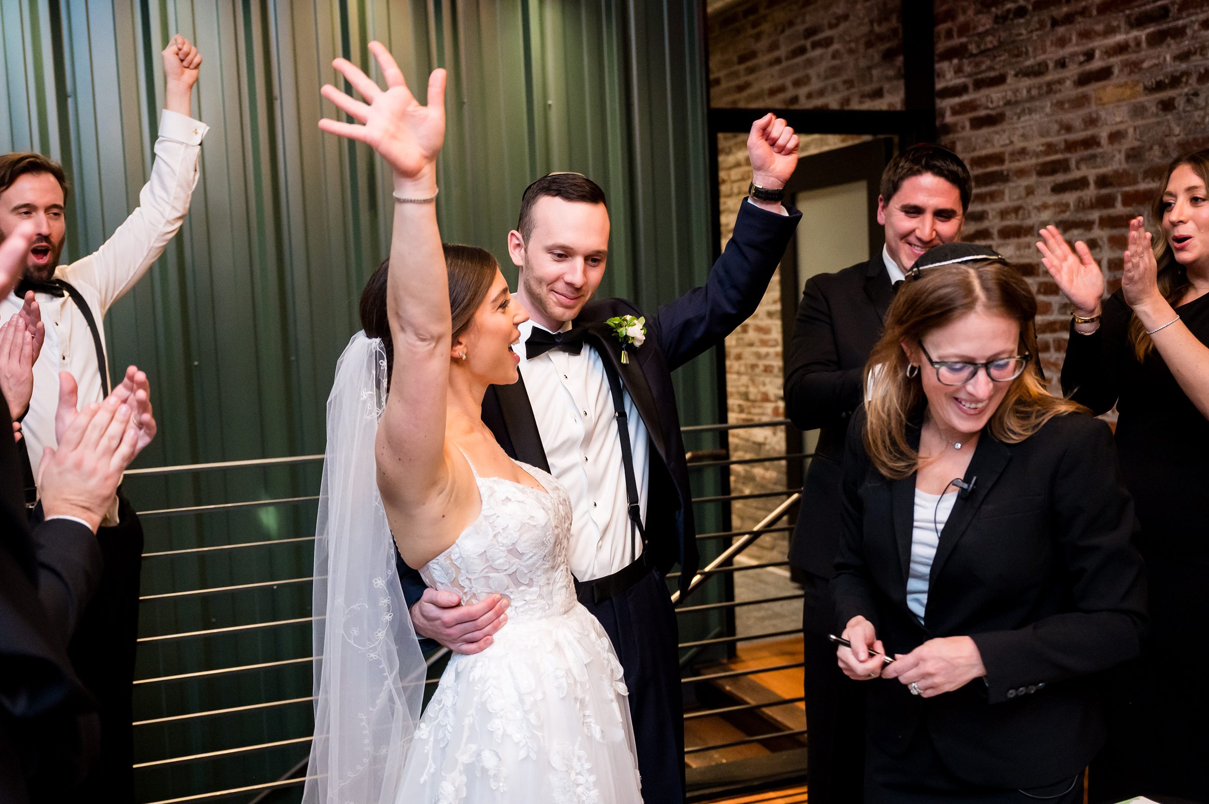 At Lilah Events wedding, the bride and groom joyfully wave their hands in the air at the reception.