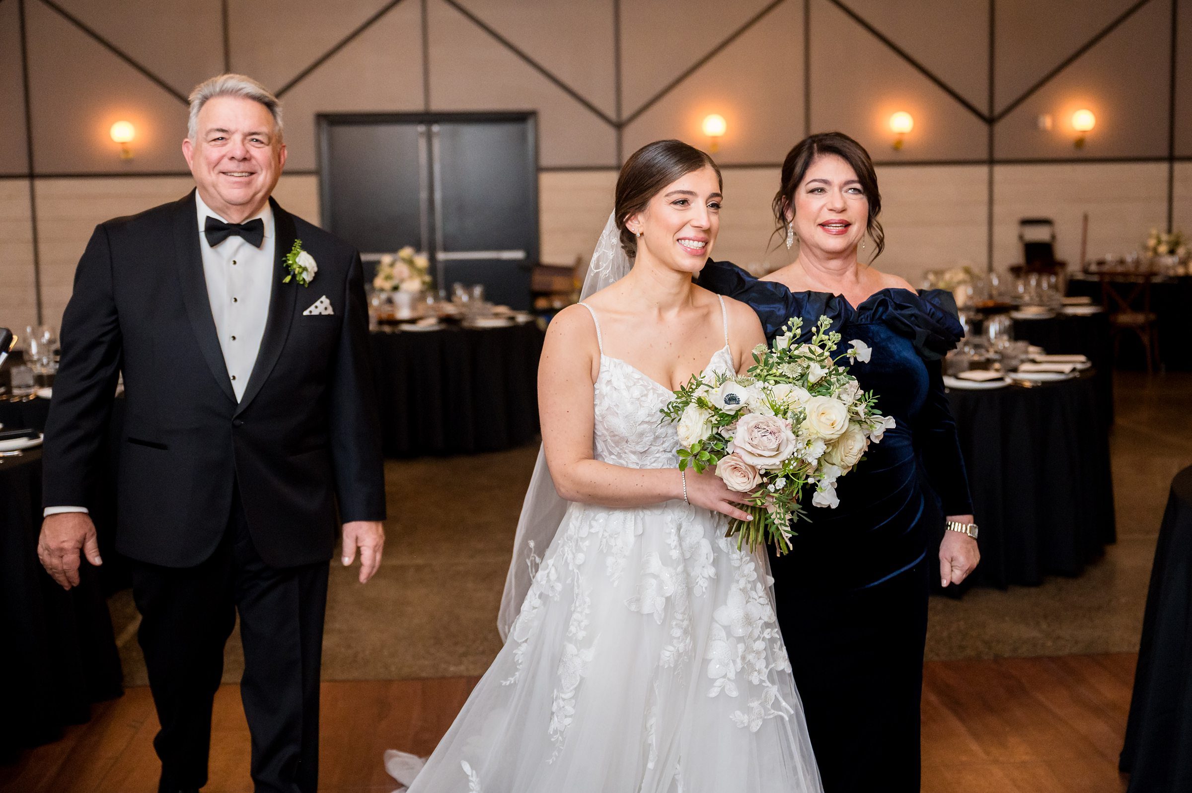 At a Lilah Events wedding, the bride gracefully walks down the aisle with her parents.