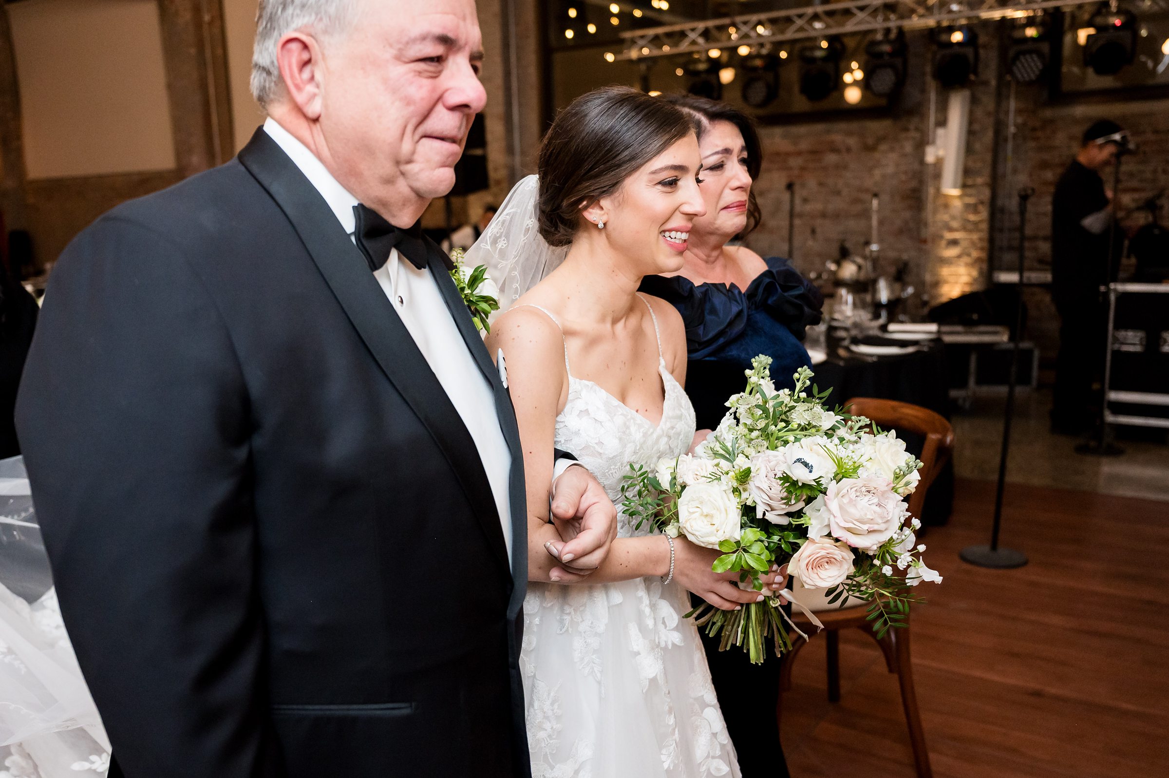 At a Lilah wedding event, a bride walks down the aisle with her father.