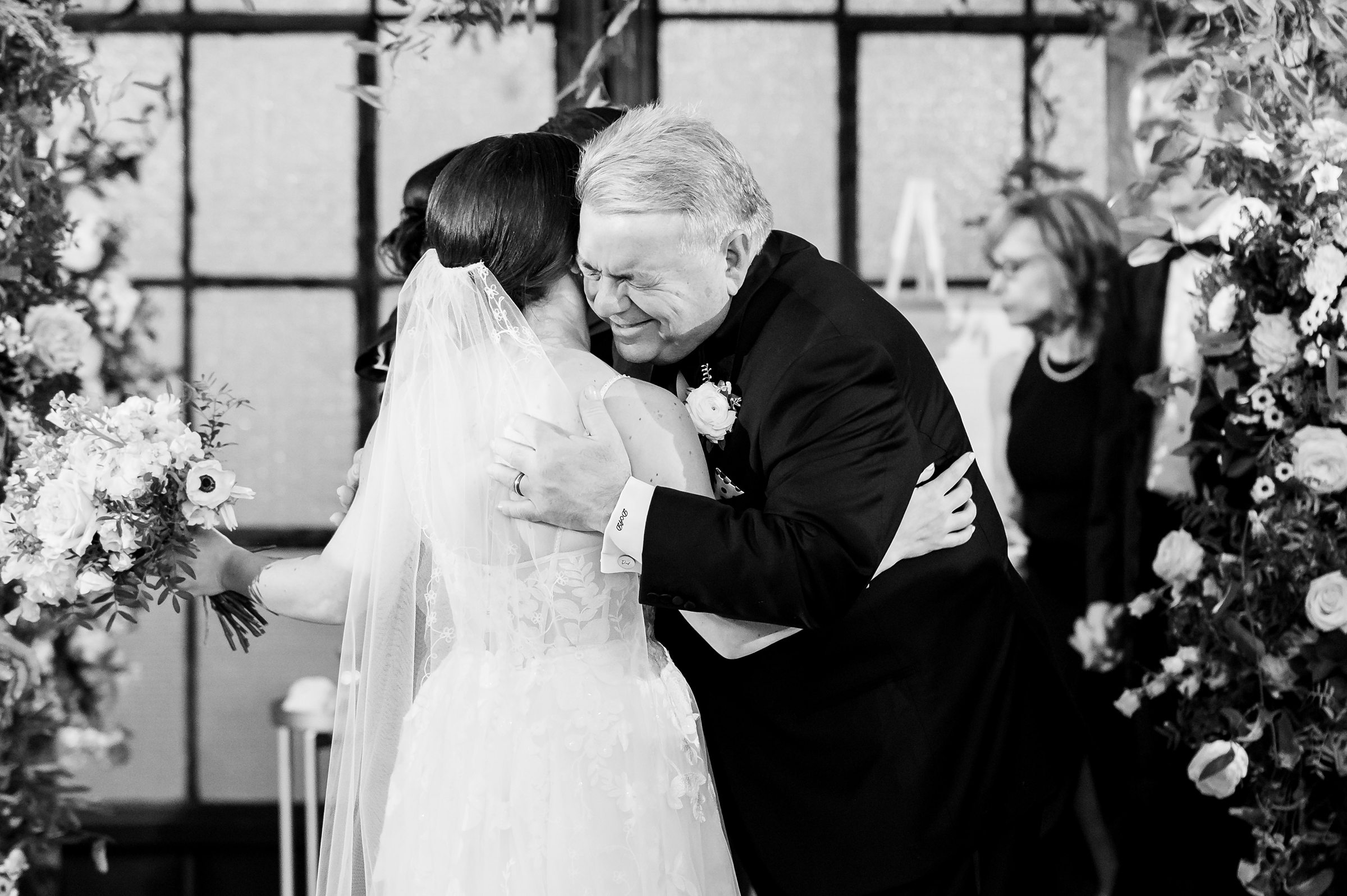 A black and white photo of a bride hugging her father at a Lilah Events wedding.