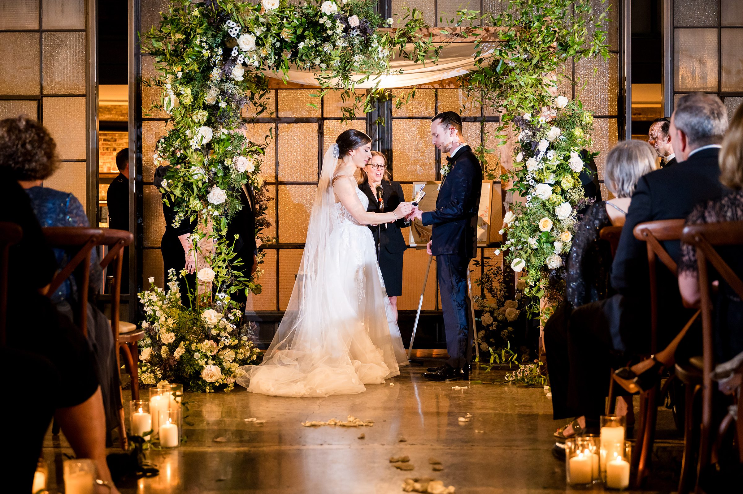 At a Lilah Events wedding, the bride and groom exchange vows under a beautiful floral arch.