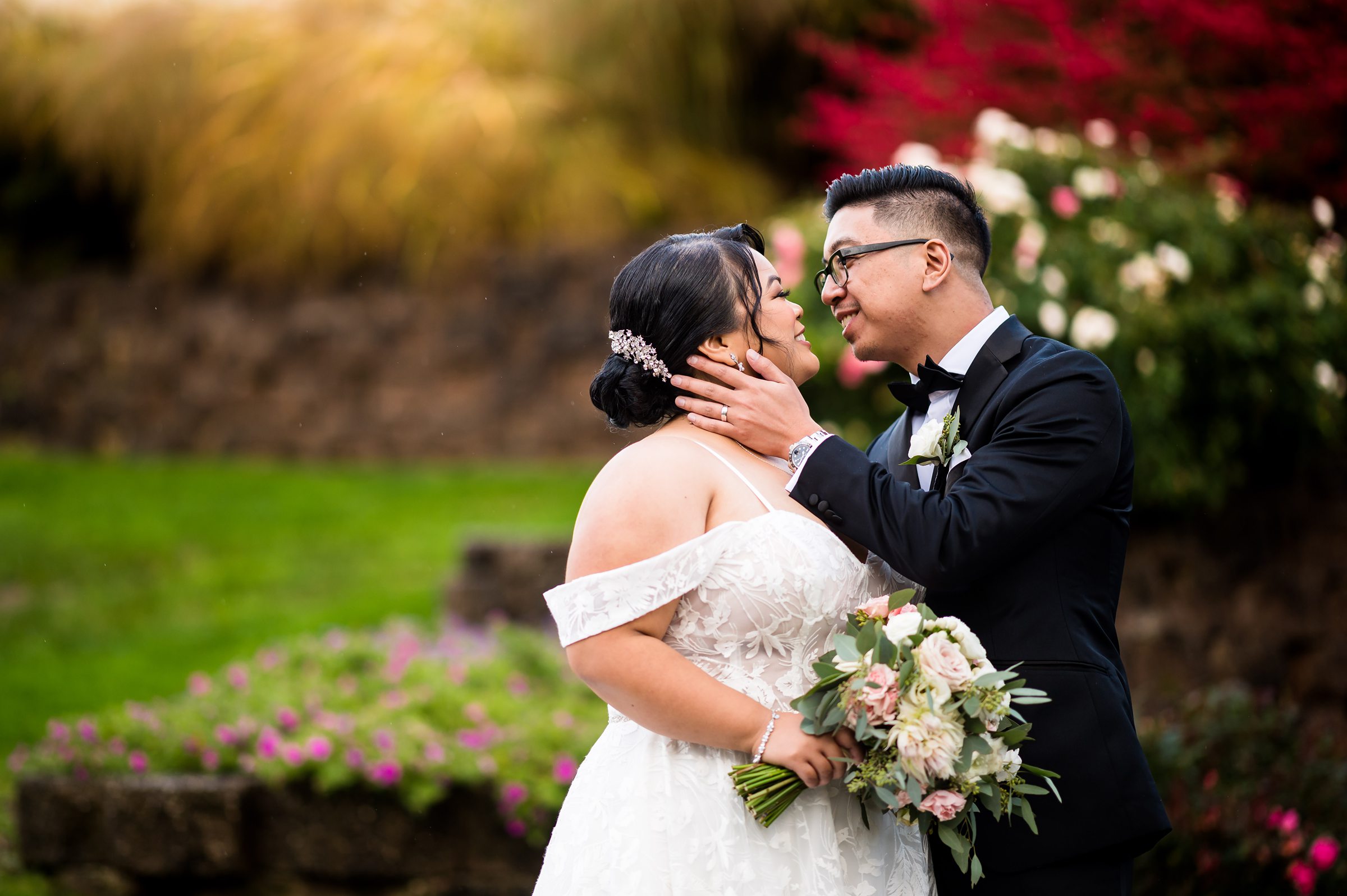 A bride and groom kissing in front of a flower garden at a Brooklake Country Club wedding.