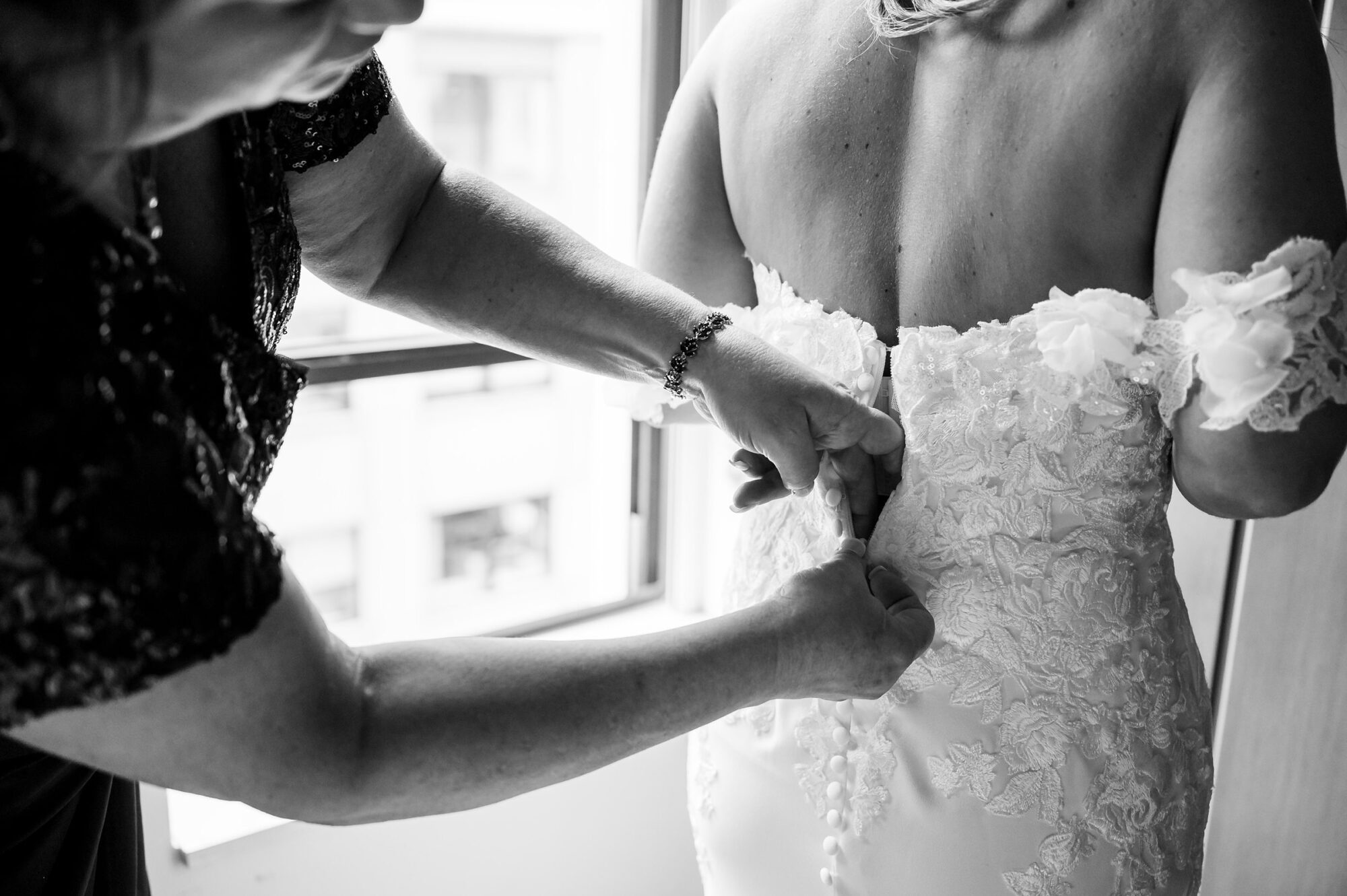 A woman putting on a bride's wedding dress.