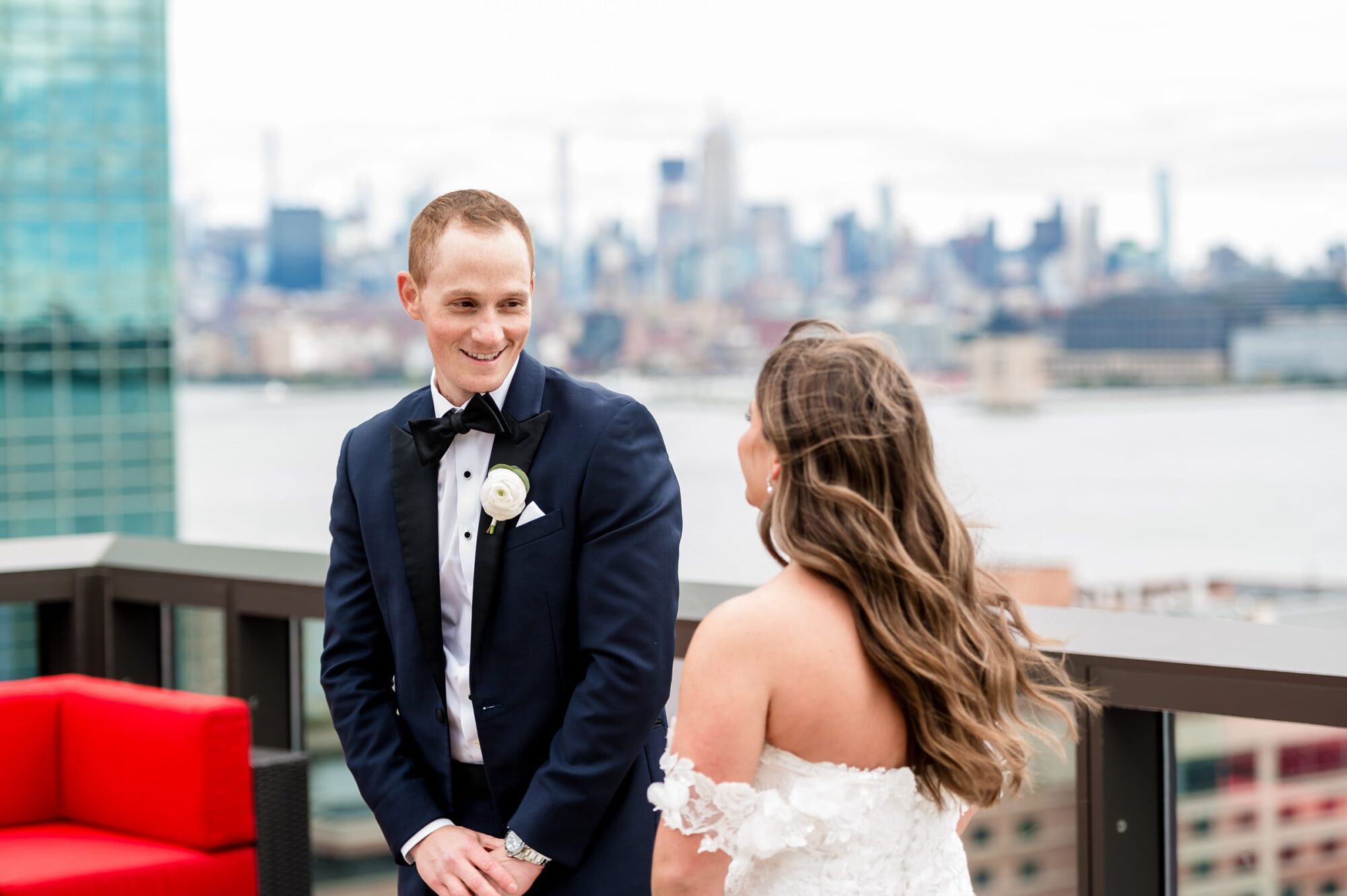 A bride and groom look at each other on a rooftop overlooking the city.