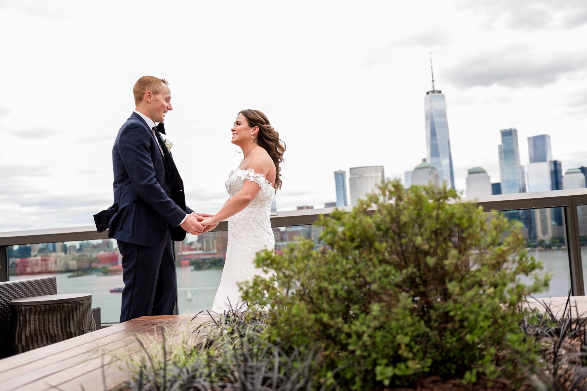 A bride and groom standing on a rooftop overlooking the city.
