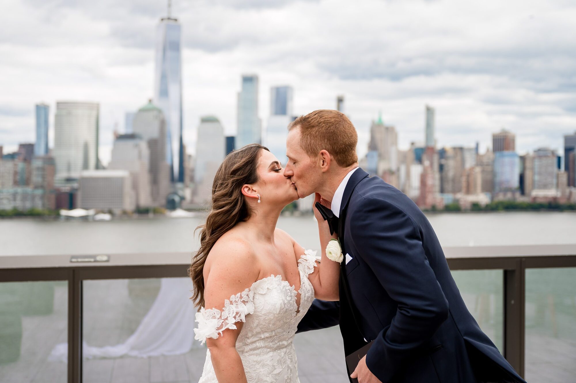 A bride and groom kiss in front of the manhattan skyline.