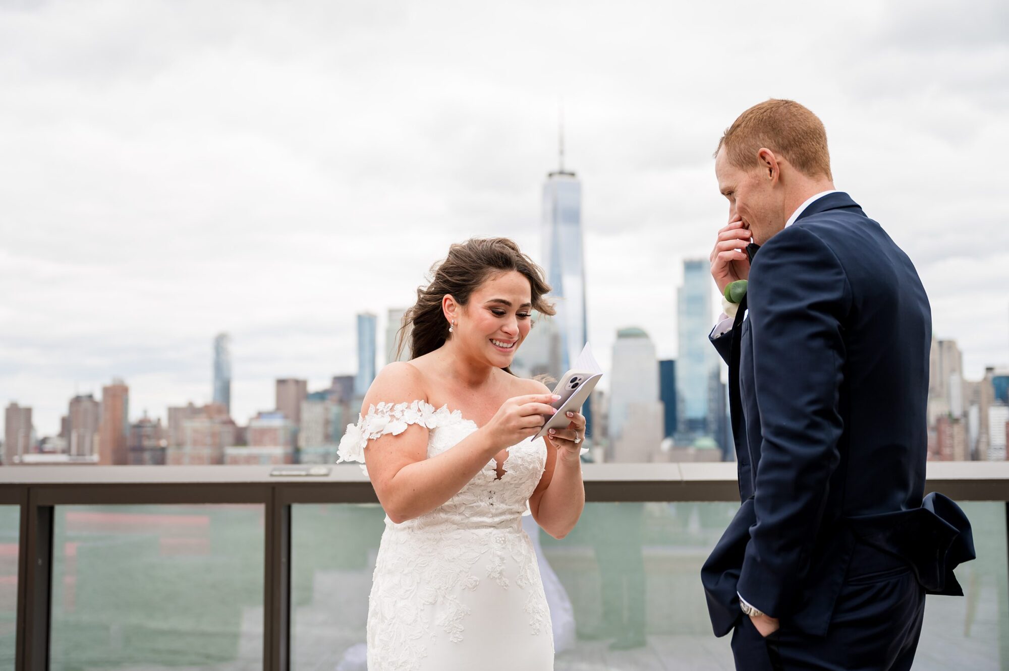 A bride and groom looking at their phone on a rooftop in nyc.