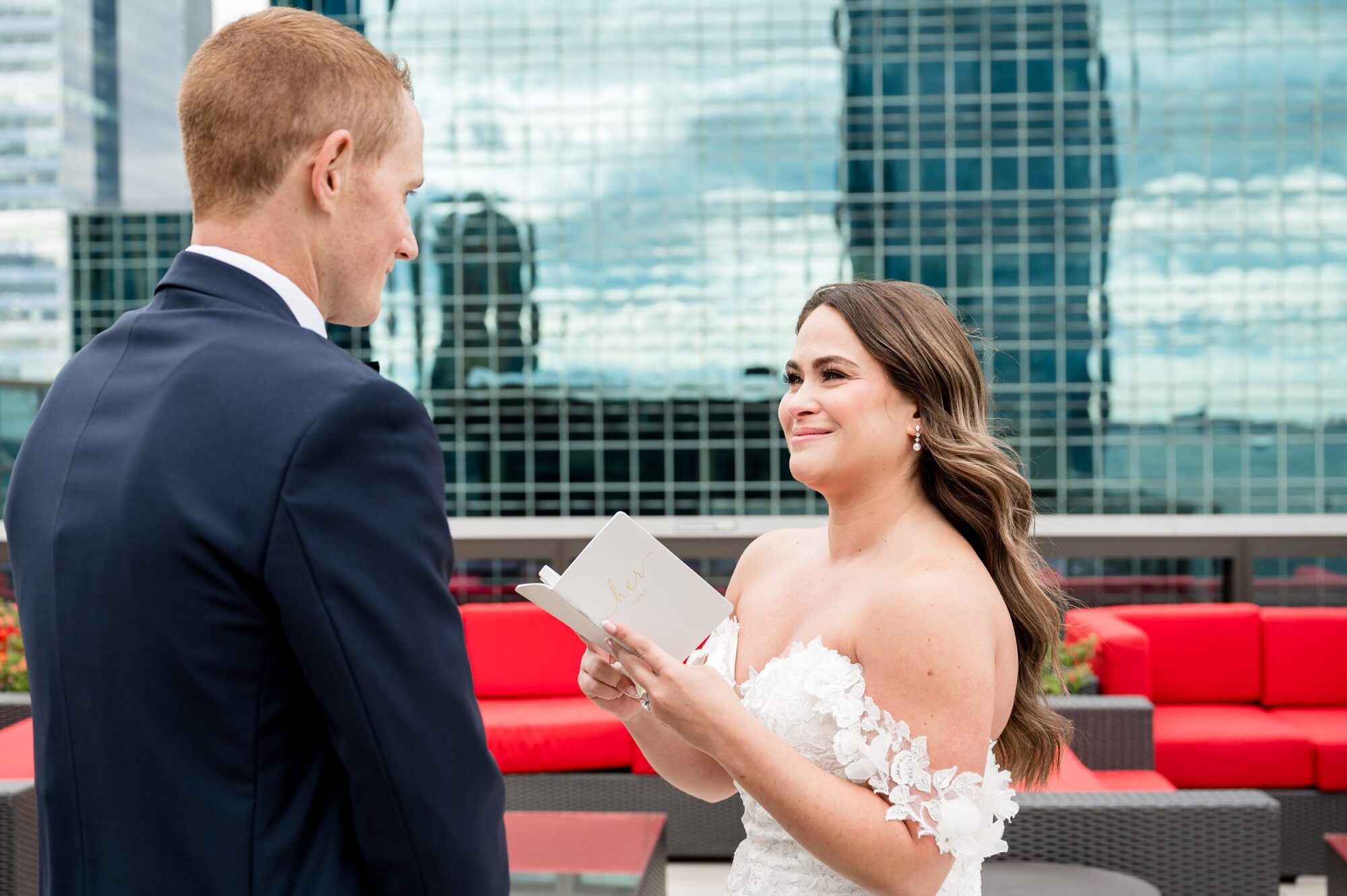 A bride and groom exchange vows in front of a city skyline.