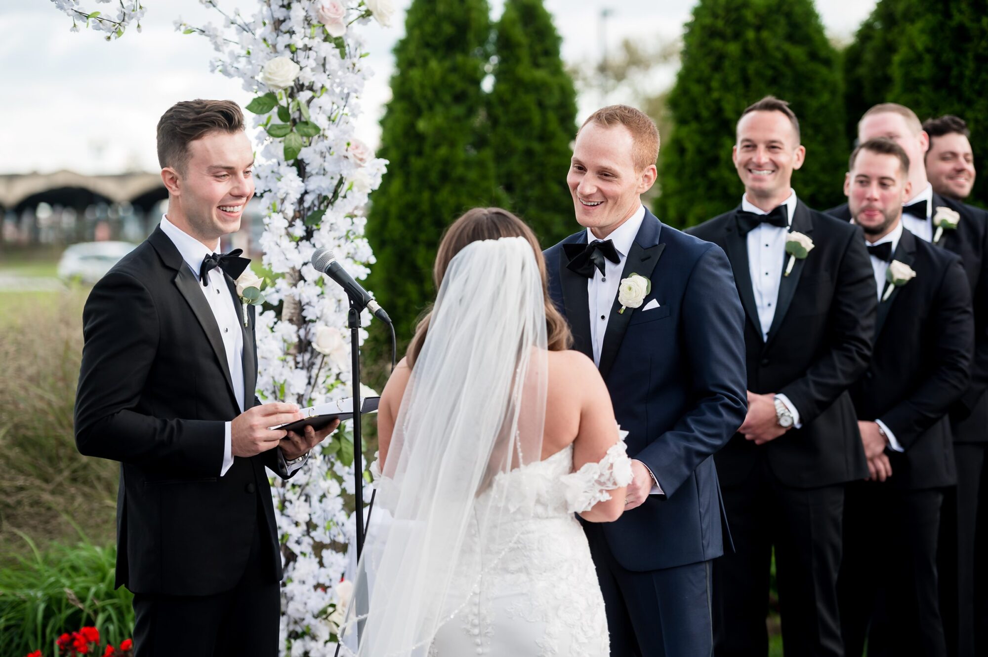 A wedding ceremony with bride and groomsmen in tuxedos.