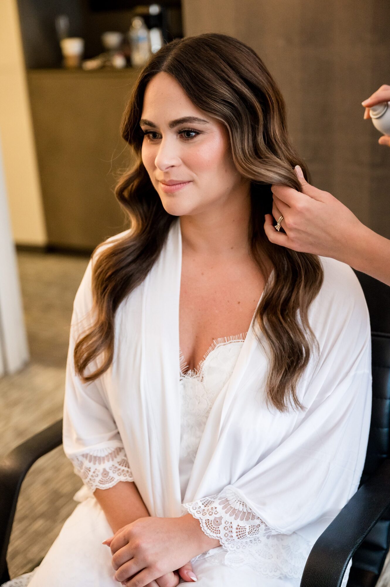 A bride getting her hair done in a robe.