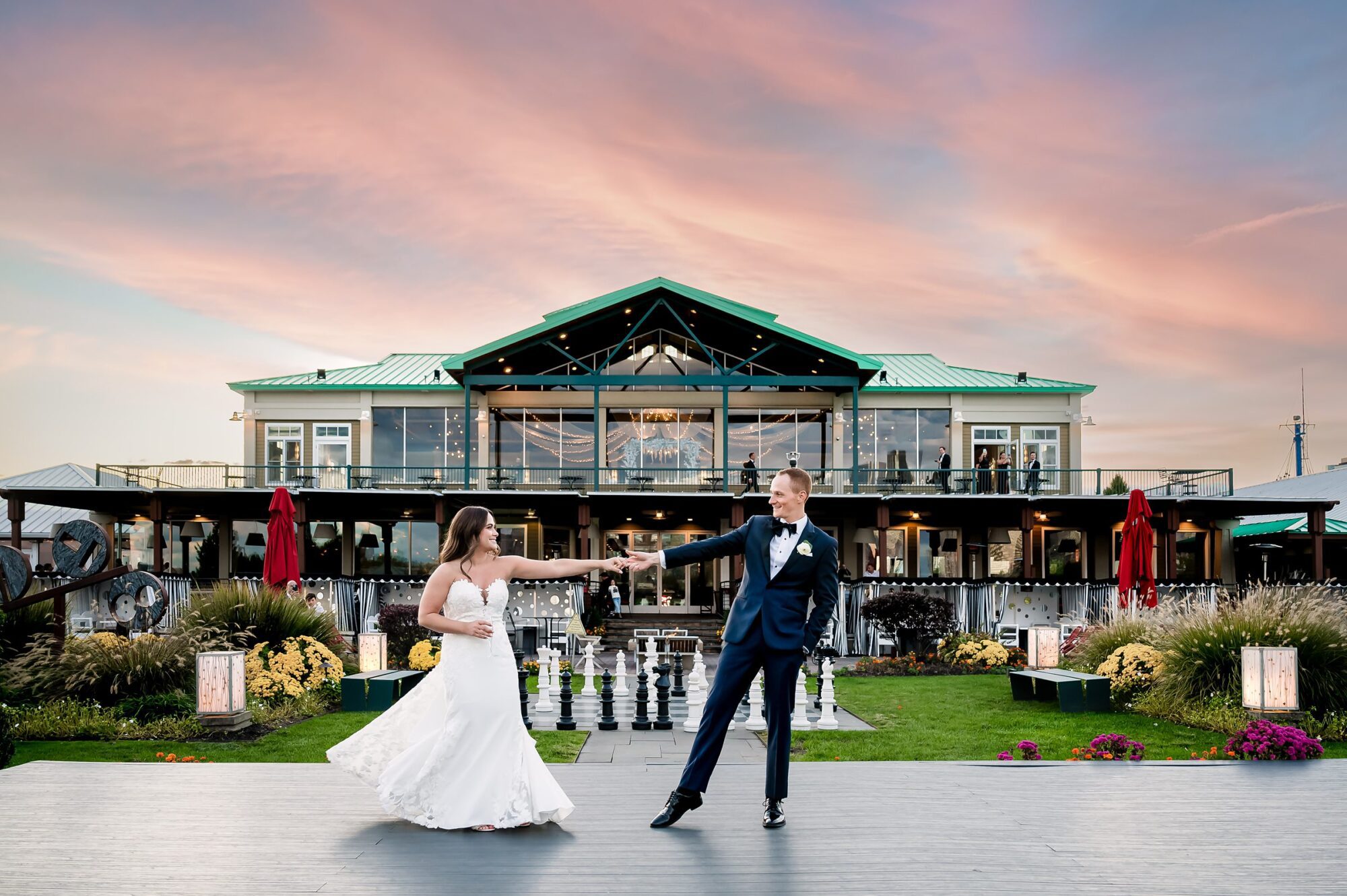 A bride and groom standing in front of a building at sunset outside of Liberty House Wedding & Event Venue.